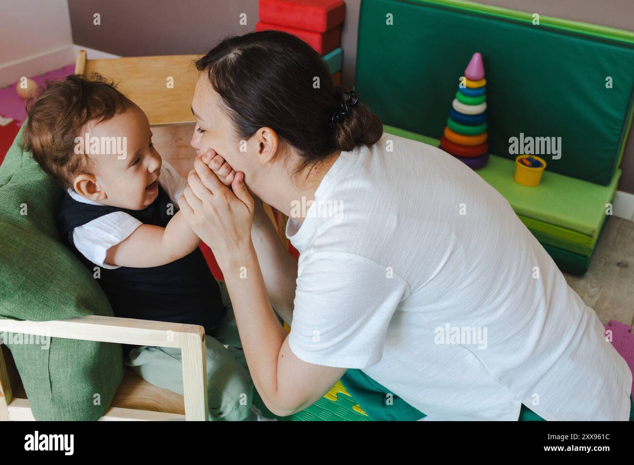 Der Physiotherapeut engagiert einen Jungen mit Körperhypotonie in spielerische Rehabilitationsaktivitäten und fördert seine körperliche und emotionale Entwicklung Stockfoto