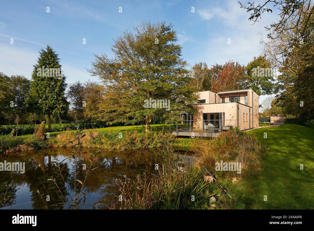 Fernsicht von der anderen Seite des Teichs auf die hintere Südhöhe des Hauses. Serenity - Scawby Brook, Scawby Brook, Großbritannien. Architec Stockfoto