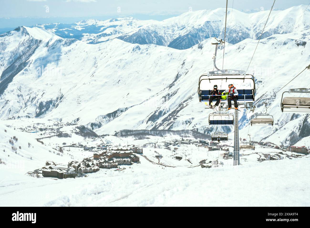 Stadtpanorama Gudauri mit Skilift im Skigebiet mit zwei männlichen Skifahrerfreunden in Gudauri in den Bergen am sonnigen Wintertag. Sport für extreme Feiertage Stockfoto