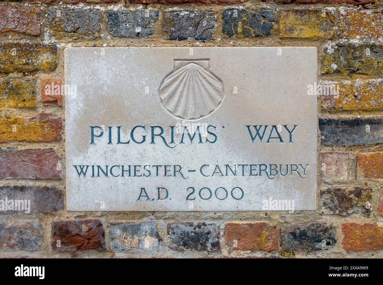 Eine Steintafel zeigt stolz den Pilgrims Way, der Reisende von Winchester nach Canterbury führt, umgeben von verwittertem Mauerwerk. England, Großbritannien Stockfoto