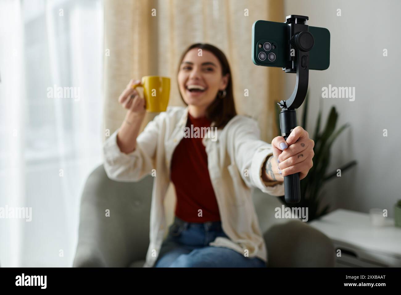 Eine junge Frau, lässig gekleidet, vloggt sich, während sie einen Smartphone-Stabilisator hält, um Videoinhalte zu erstellen. Stockfoto