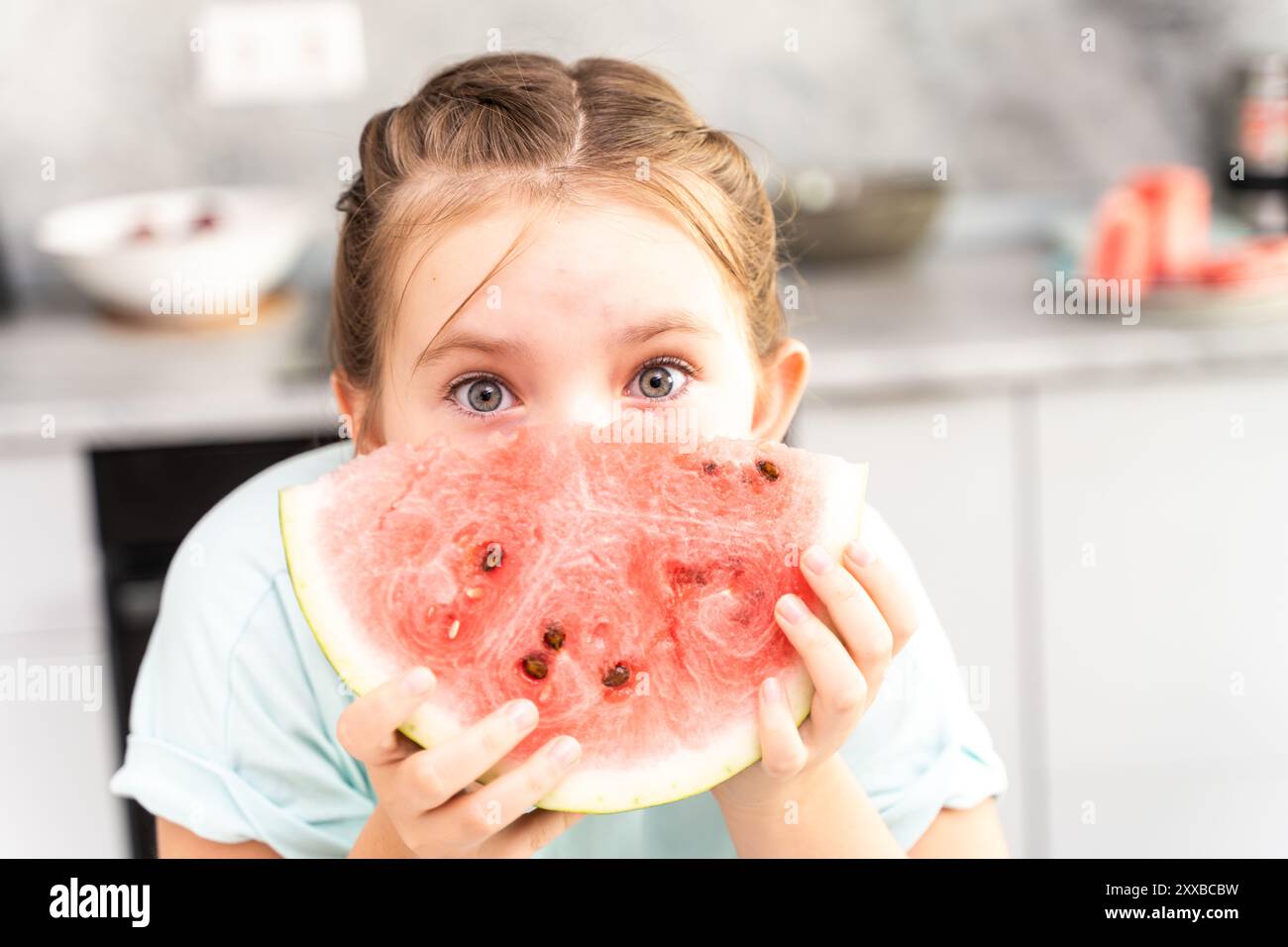 Porträt eines fröhlichen kleinen Mädchen aus der Jugend mit einer Wassermelone. Sie hält ein Stück in den Händen und bedeckt ihr Gesicht damit vor dem Hintergrund Stockfoto