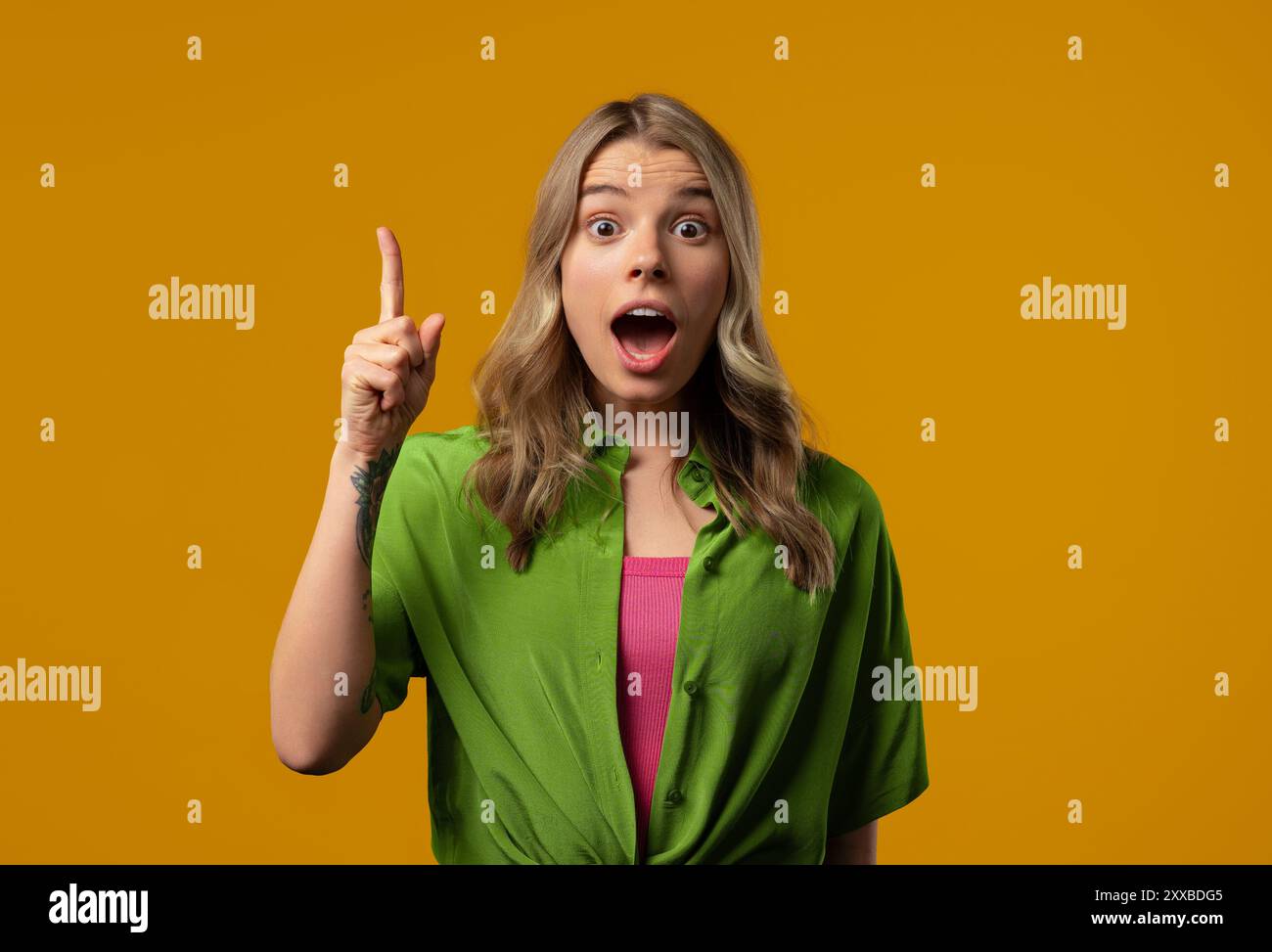 Glückliche, stilvolle Frau, die eine Idee von eureka hat, mit dem Finger auf gelbem Hintergrund nach oben zeigt. Eine clevere Dame, die eine Geste zeigte oder sich daran erinnerte, was sie fälschte Stockfoto