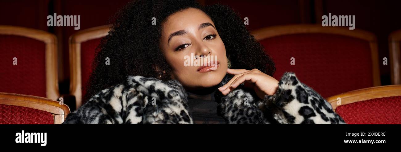 Eine stilvolle Frau in einem Mantel mit Leopardenmuster schaut sich einen Film an, ihr Ausdruck fesselnd. Stockfoto