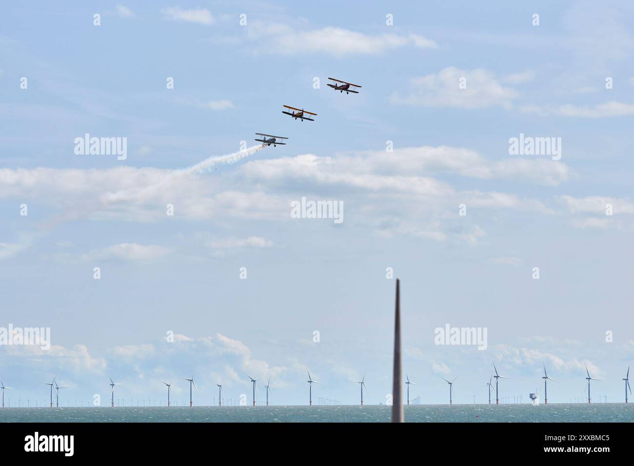 Clacton on Sea, Großbritannien, 24. August 2024. An einem Sommertag fliegen 3 Stampen-Doppelflugzeuge über den Strand von Clacton. Im Bild ist die Windfarm Gunfleet Sands. Quelle: Martin Suker/Alamy Live News Stockfoto