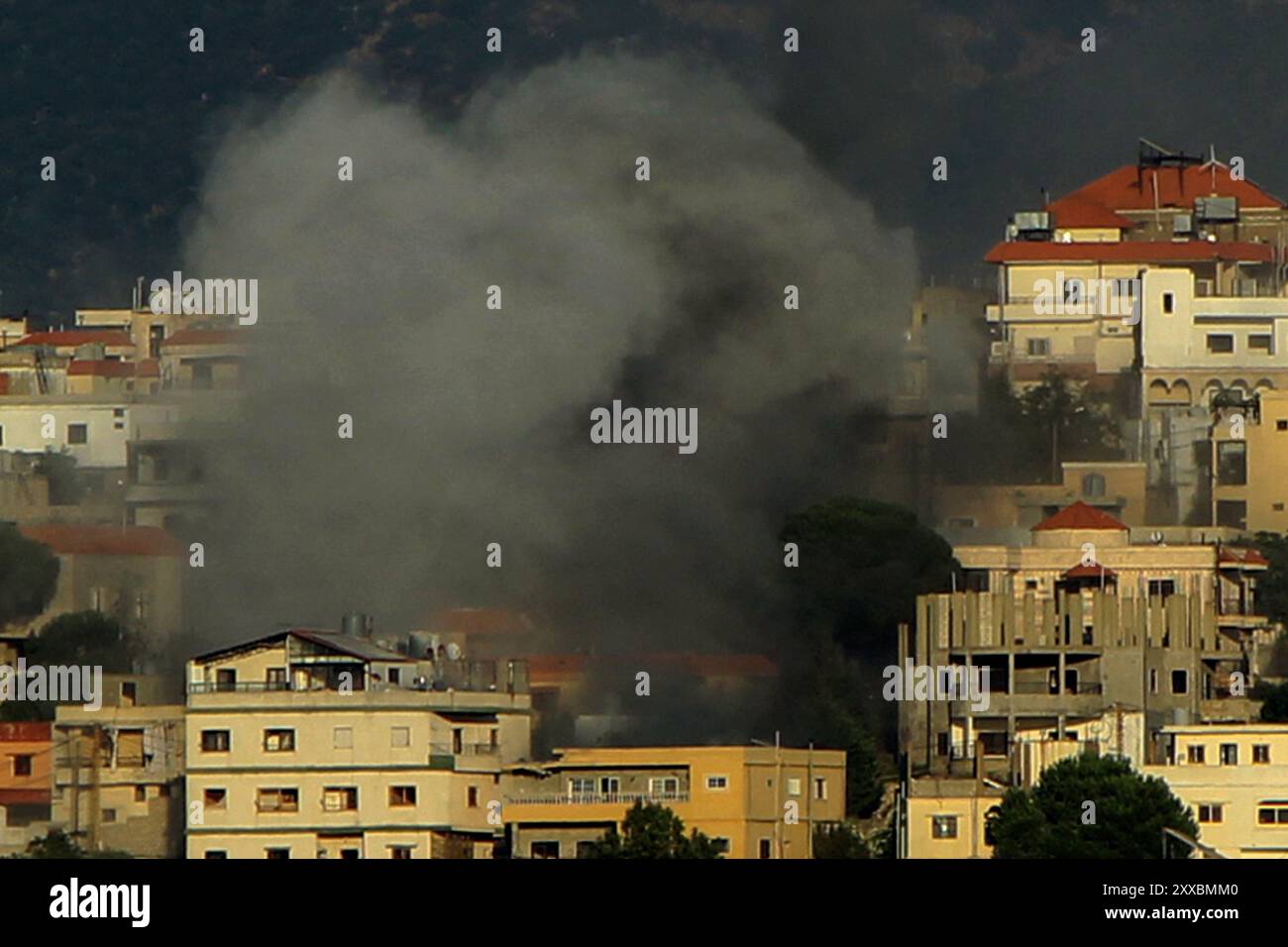 Qliyaa, Qlyiaa, Libanon. August 2024. Zwischen Häusern in der libanesischen südlichen Grenzstadt Khiam weht starker Rauch von einem israelischen Beschuss. Sieben pro-iranische Hisbollah-Kämpfer und ein Kind wurden bei israelischen Angriffen im Südlibanon getötet, als die bewaffnete Gruppe Hisbollah mit Artilleriegeschossen und Raketen über die Grenze reagierte. Das israelische Militär hat parallel zum Gazastreifen-Krieg über die Südgrenze des Libanon hinweg Feuer mit der Hisbollah verhandelt, wobei die Feindseligkeiten in jüngster Zeit angesichts der Befürchtungen, dass ein regionaler Krieg ausbrechen könnte, verstärkt werden. (Kreditbild: © Marwan Naamani/ZUMA Press Stockfoto