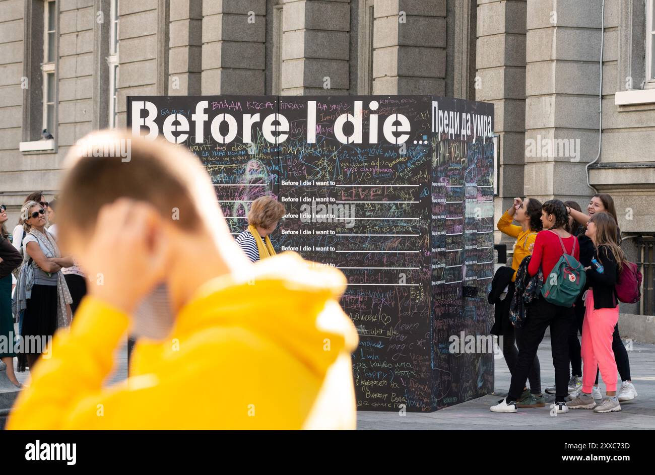 Passanten schreiben und lesen Nachrichten an einer Tafel oder an einer Tafel für das interaktive Kunstprojekt Before I die Public in Sofia Bulgarien, EU Stockfoto