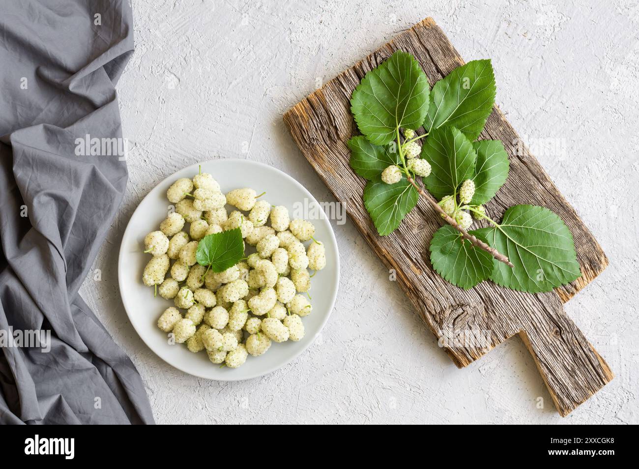 Frische weiße Maulbeeren im Teller mit Zweig auf hölzernem Hintergrund, Sommerfrucht-Konzept Stockfoto