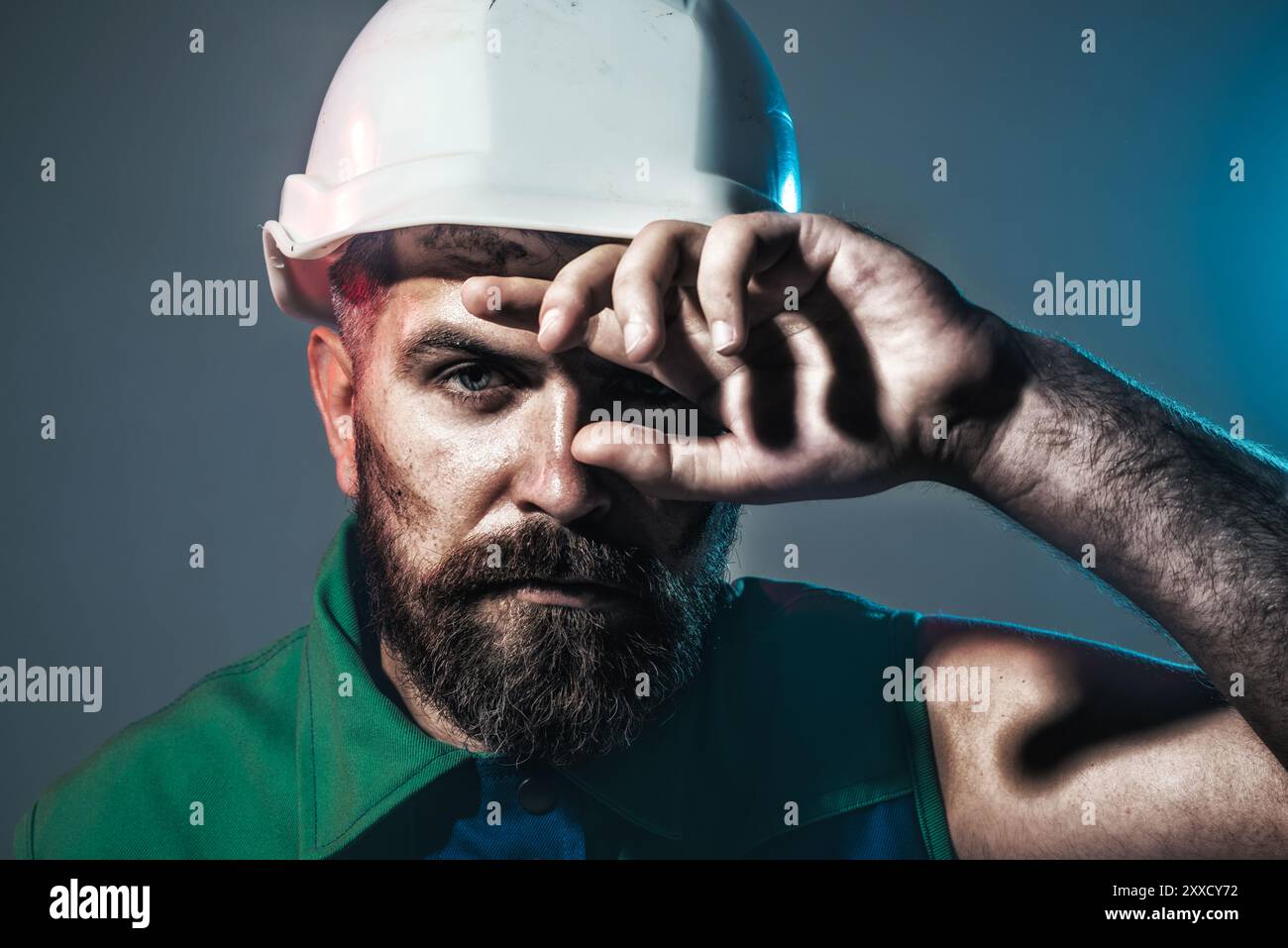 Harte Arbeit auf der Baustelle. Müder Baumeister im Schutzhelm wischt Schweiß von der Stirn ab. Schwerberufsstand. Ermüdeter Industriearbeiter mit Schutzhelm Stockfoto