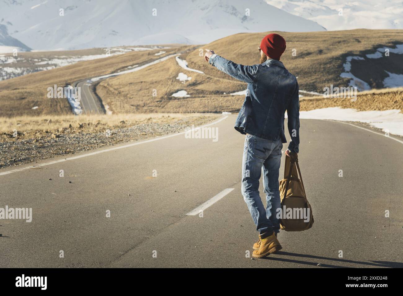 Tourismus- und Menschenkonzept, stylischer Hipster, der draußen auf der Landstraße spaziert und mit dem Finger auf etwas zeigt Stockfoto