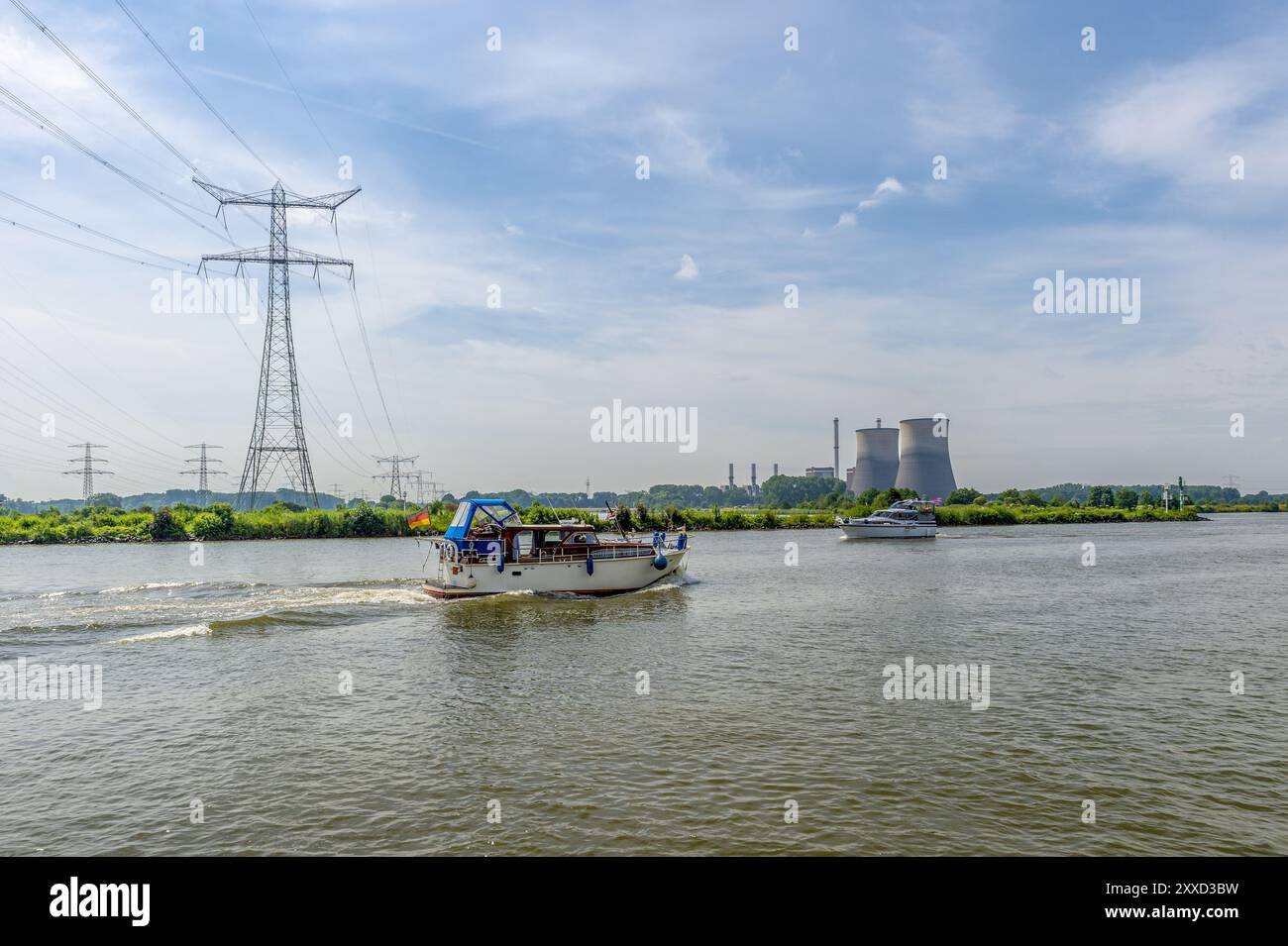 Eine Motoryacht auf der Maas unter einer Hochspannungsleitung und vor einem Gaskraftwerk Stockfoto