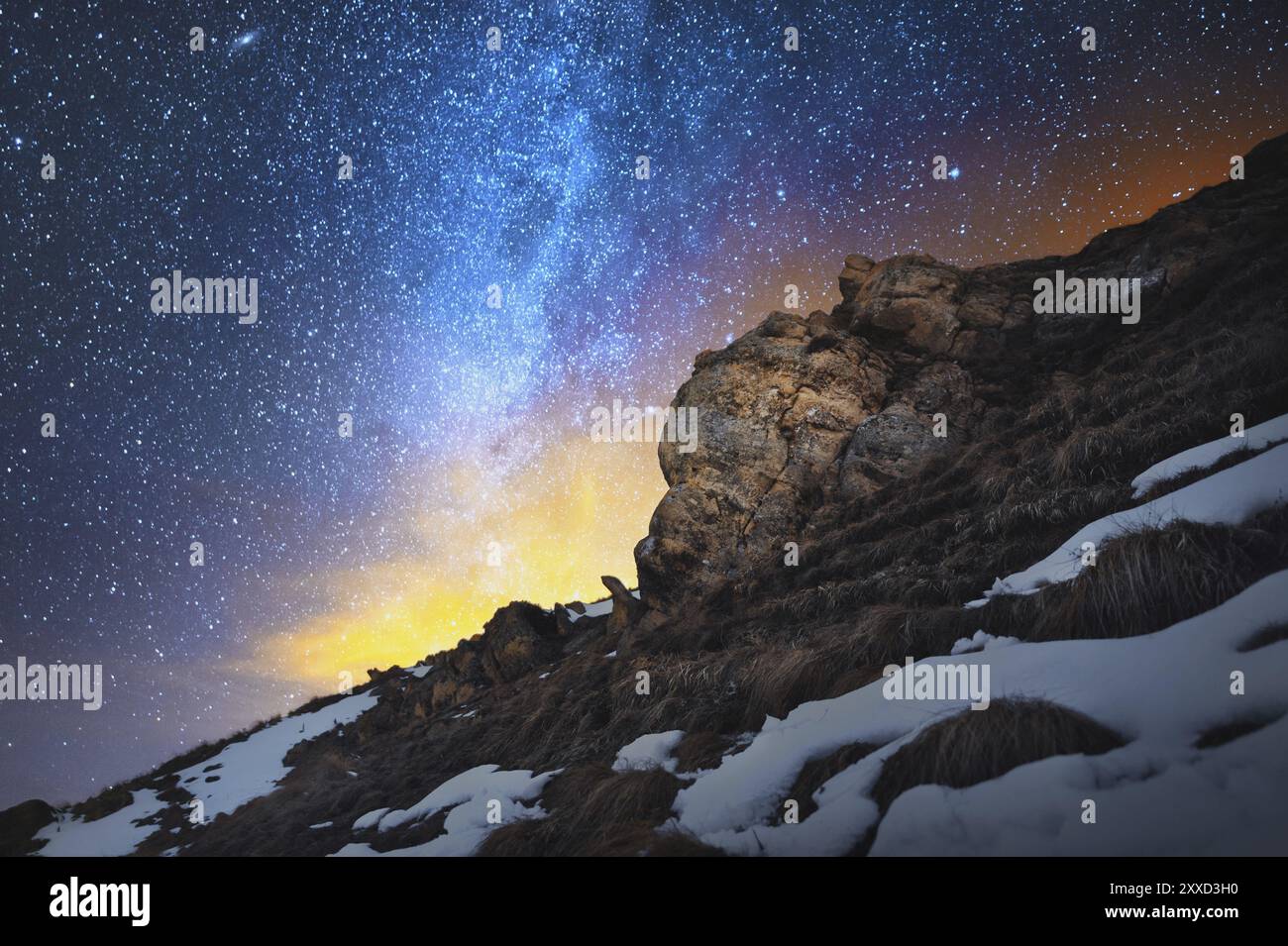 Nächtliche Szenen bei langer Belichtung. Eine wunderschöne kaukasische Landschaft mit roten Felsen vor dem Hintergrund der kalten Milchstraße und einer warmen gelblichen Re Stockfoto