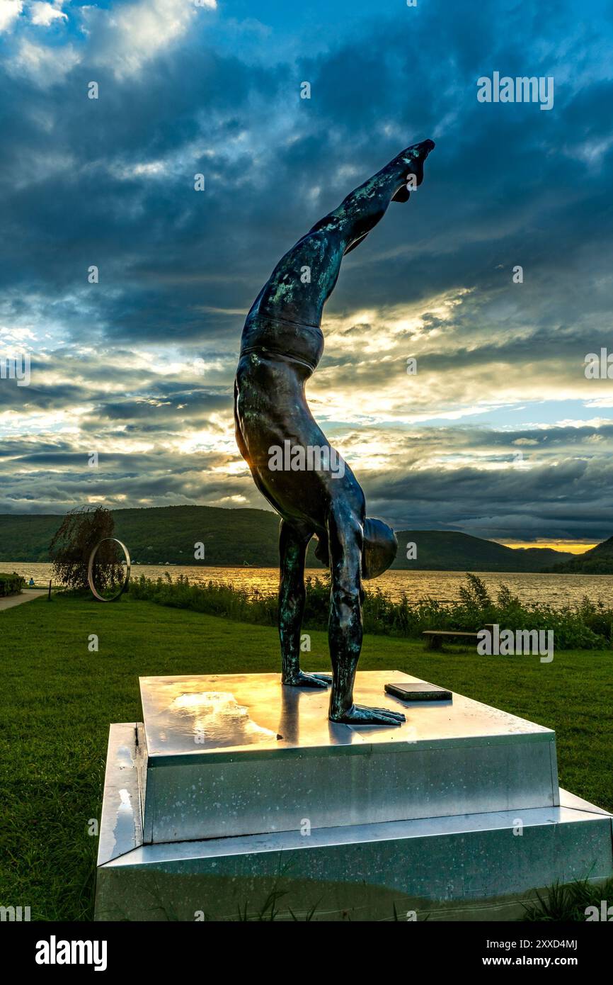 Peekskill, NY - US - 19. August 2024 Feuermans Bronzestatue „The Golden Mean“ zeigt einen Taucher in einem Handstand, getaucht in goldenem Sonnenuntergangslicht, mit einer se Stockfoto