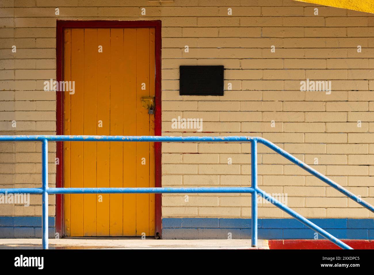 Gelbe Tür mit rotem Rand und blauen Details Stockfoto