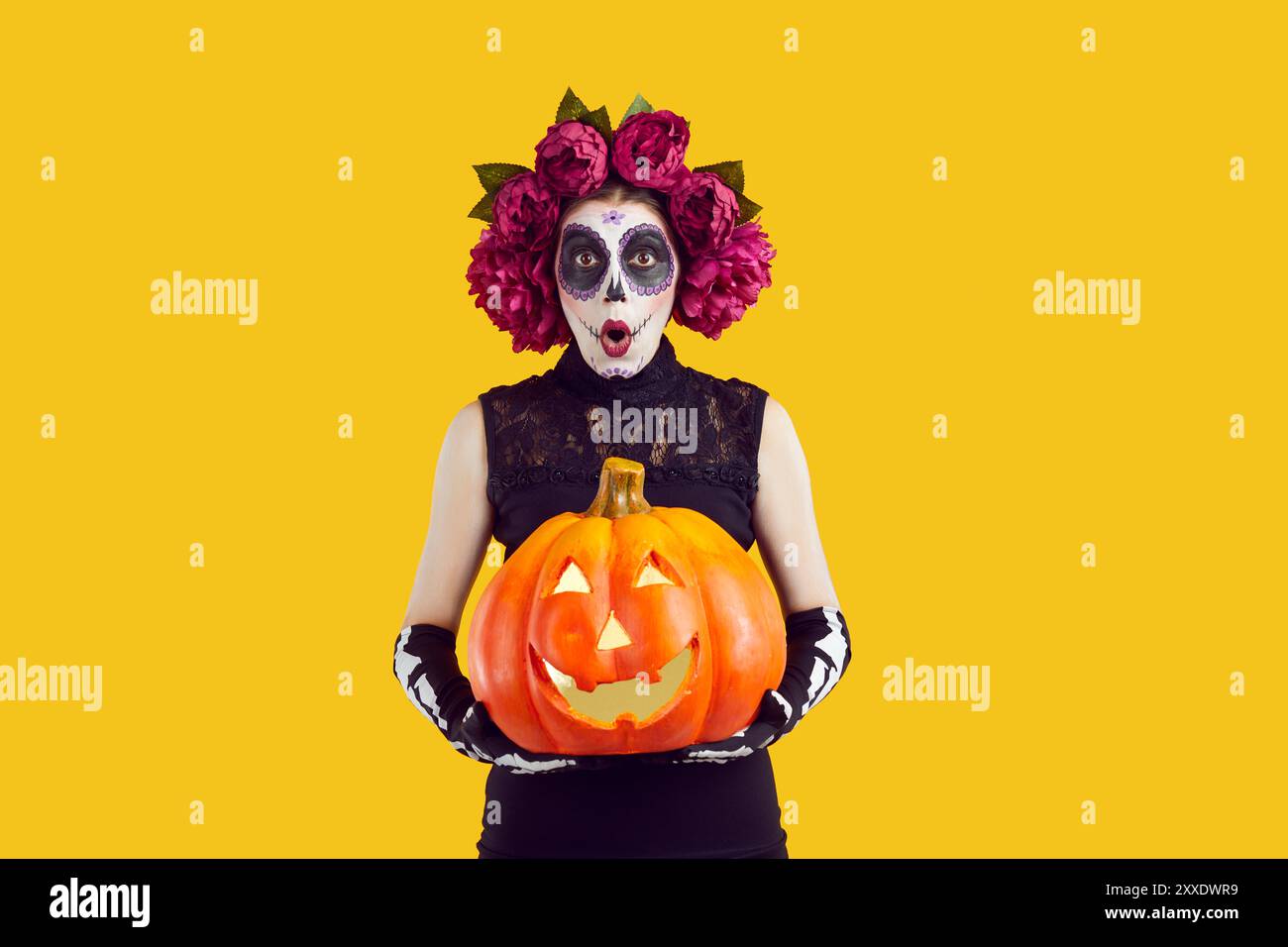 Frau im Halloween-Kostüm mit Kürbis, der in die Kamera schaut, mit lustigem überraschtem Gesichtsausdruck Stockfoto