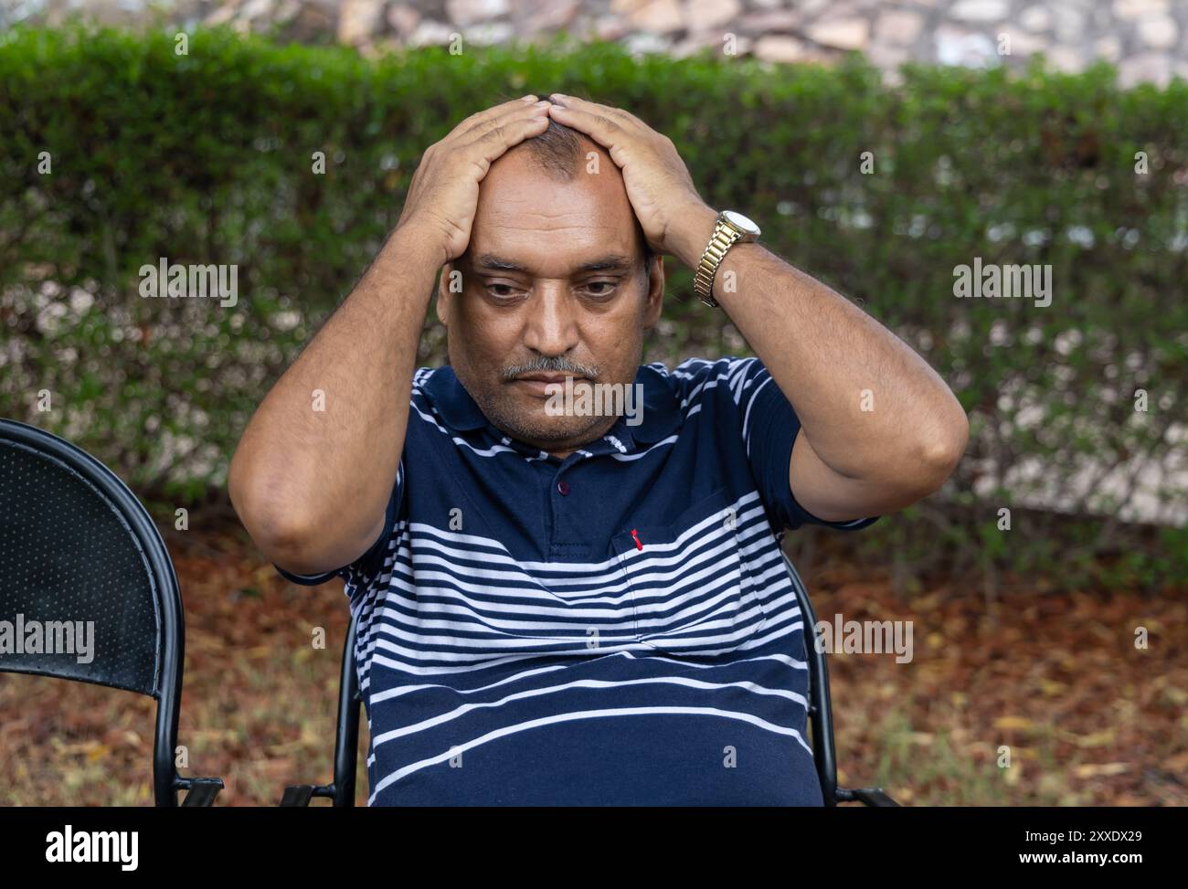 Isolierter allein Mann in Depression, der abends aus flachem Winkel im Park sitzt Stockfoto