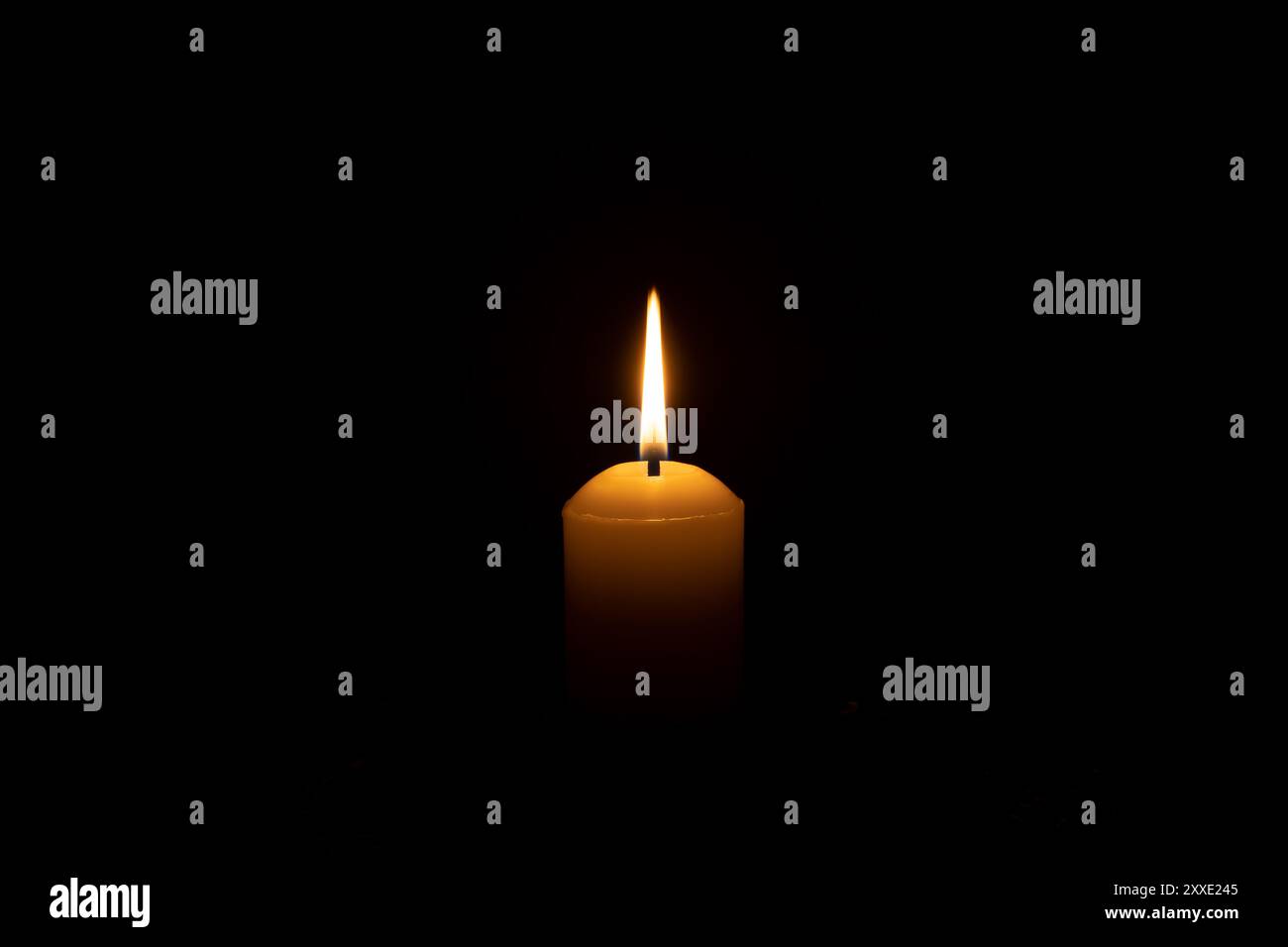 Ein einzelnes Kerzenlicht leuchtet auf einer großen weißen Kerze auf dem Tisch in der Kirche zu Weihnachten, Beerdigung oder Gedenkfeier mit Kopierraum ist auf Schwarz isoliert Stockfoto