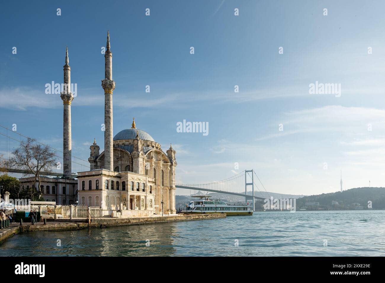 Blick auf den Sonnenuntergang auf die Bosporusbrücke in Istanbul, Türkei, mit dem ruhigen Wasser des Bosporus und einem warmen, goldenen Himmel, der eine ruhige Atmosphäre schafft Stockfoto