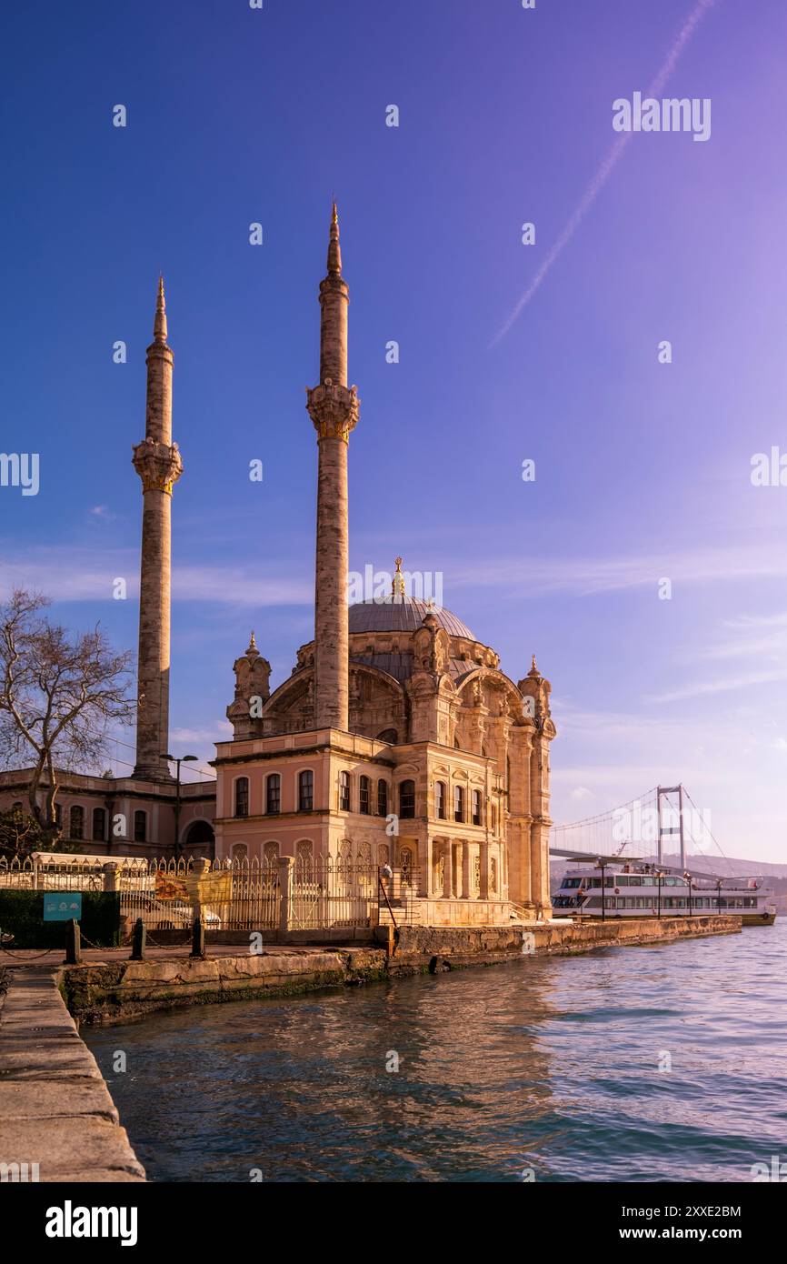 Blick auf den Sonnenuntergang auf die Bosporusbrücke in Istanbul, Türkei, mit dem ruhigen Wasser des Bosporus und einem warmen, goldenen Himmel, der eine ruhige Atmosphäre schafft Stockfoto