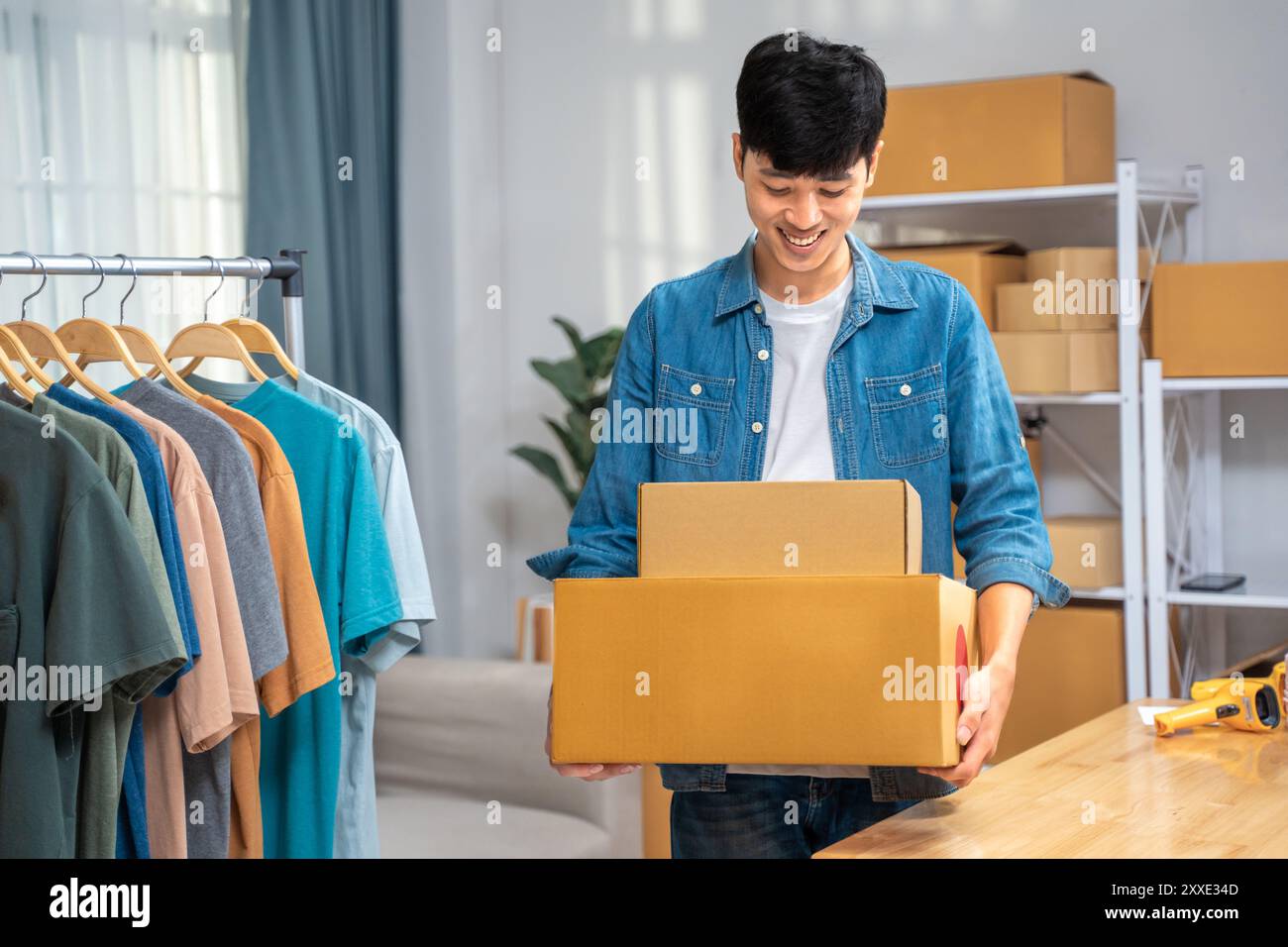 Glücklicher junger Online-Verkäufer, der seine verpackten Produktboxen hält, um sie an seinen Kunden zu senden Stockfoto