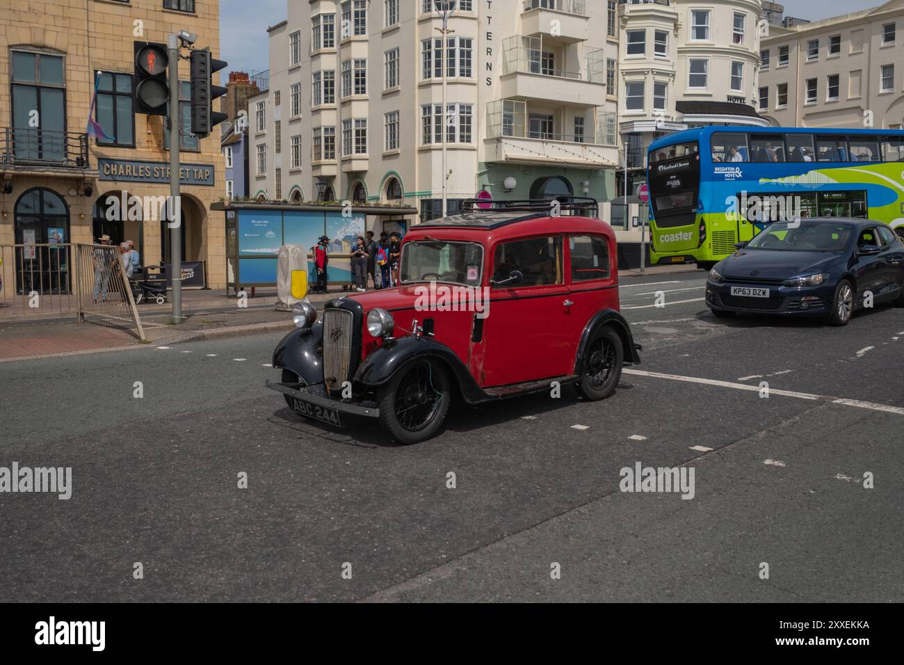 An einem sonnigen Sommertag fährt ein roter Oldtimer von Austin sieben entlang der Küste von Brighton. Stockfoto