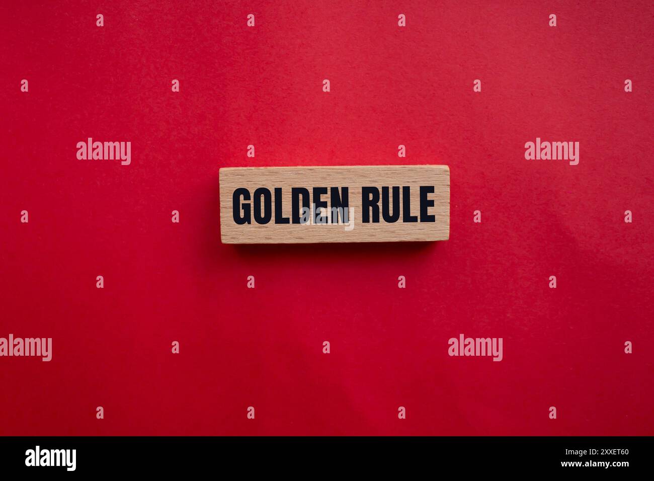 Goldene Regelbotschaft auf Holzblock mit rotem Hintergrund geschrieben. Konzeptionelles goldenes Regelsymbol. Kopierbereich. Stockfoto