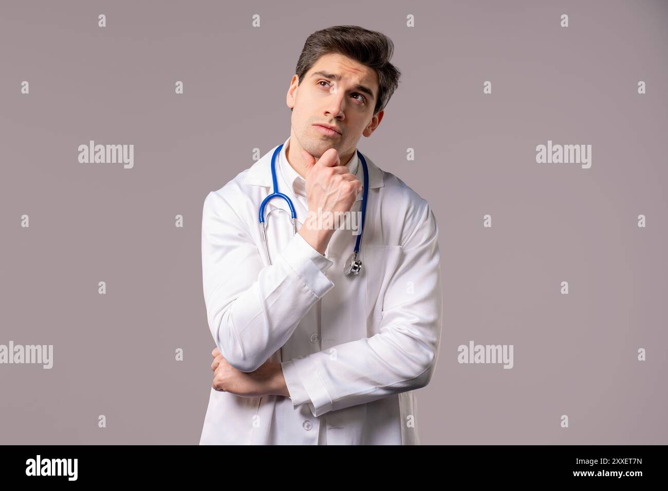 Lächelnder reifer Arzt Mann in weißer medizinischer Mantelform, der auf leeren Platz für Ihre Werbung sucht. Empfehlender Facharzt, der nach rechts zeigt Stockfoto