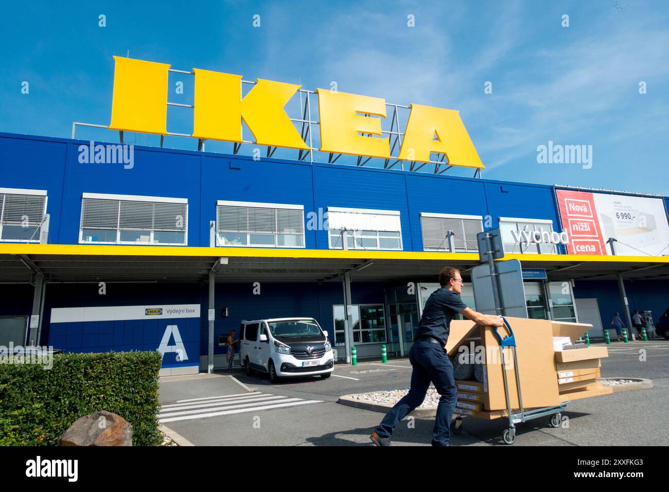 Unterschreibe das Ikea-Logo gegen den blauen Himmel, der den Wagen schiebt Stockfoto