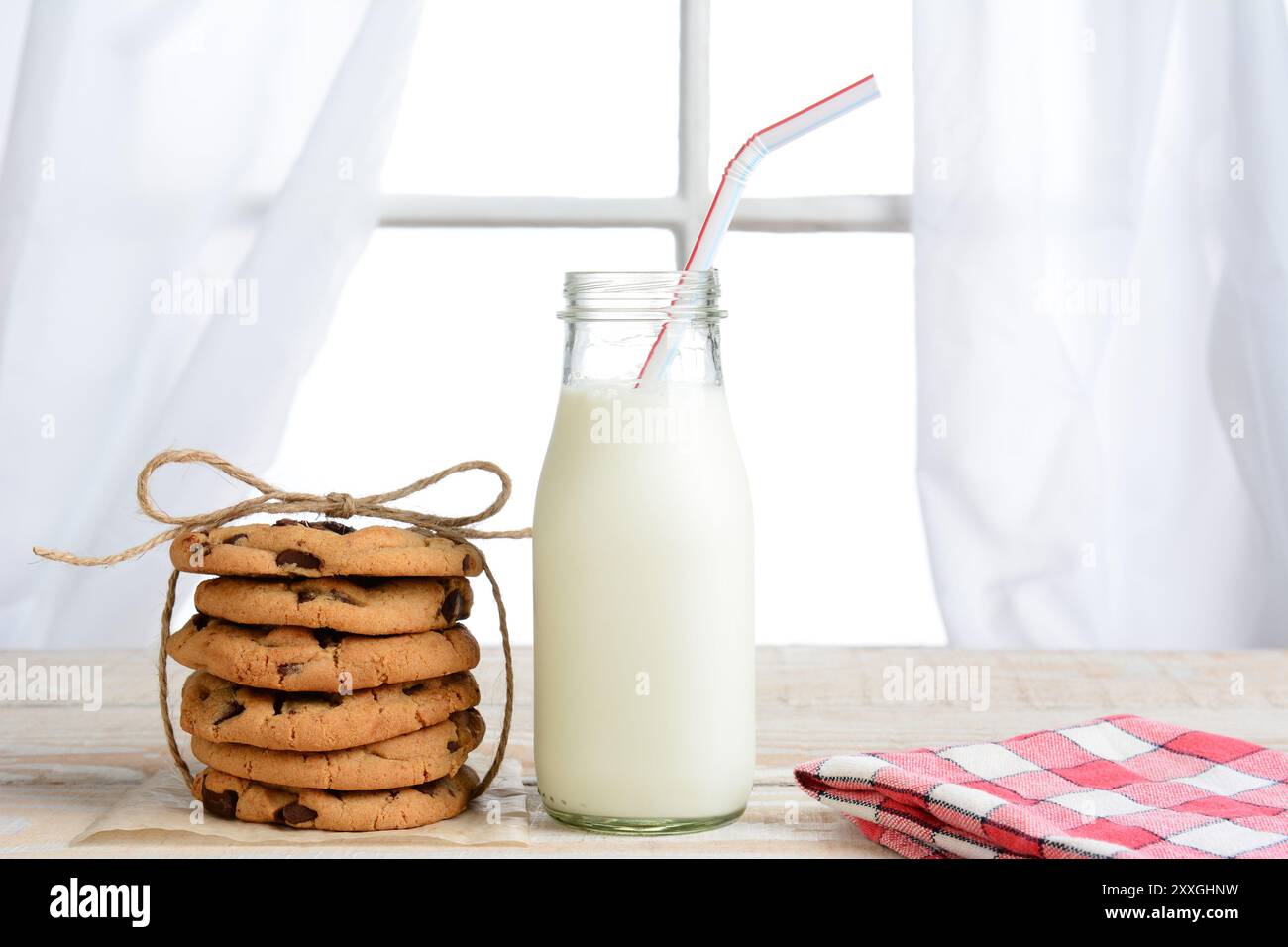 Horizontale Aufnahme eines After-School-Snacks mit Schokoladenchips-Keksen und einer altmodischen Flasche Milch. Die Kekse sind mit Garn und einem Nickerchen gebunden Stockfoto