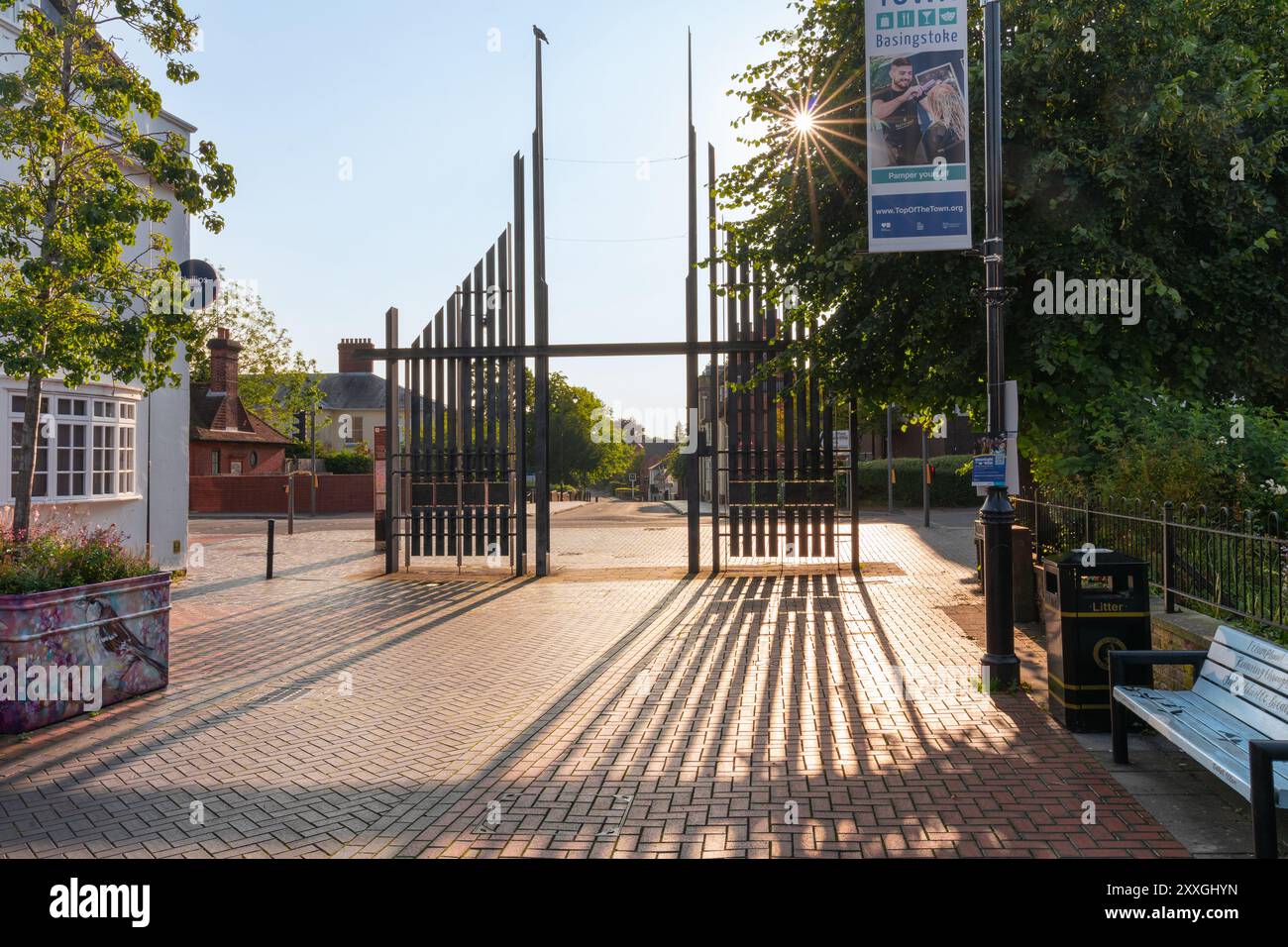 Sonnenbildende Beugungsspitzen und ein Starburst-Effekt durch die Triumphtore aus Stahl an der London Street, Basingstoke an einem frühen Sommermorgen. Stockfoto