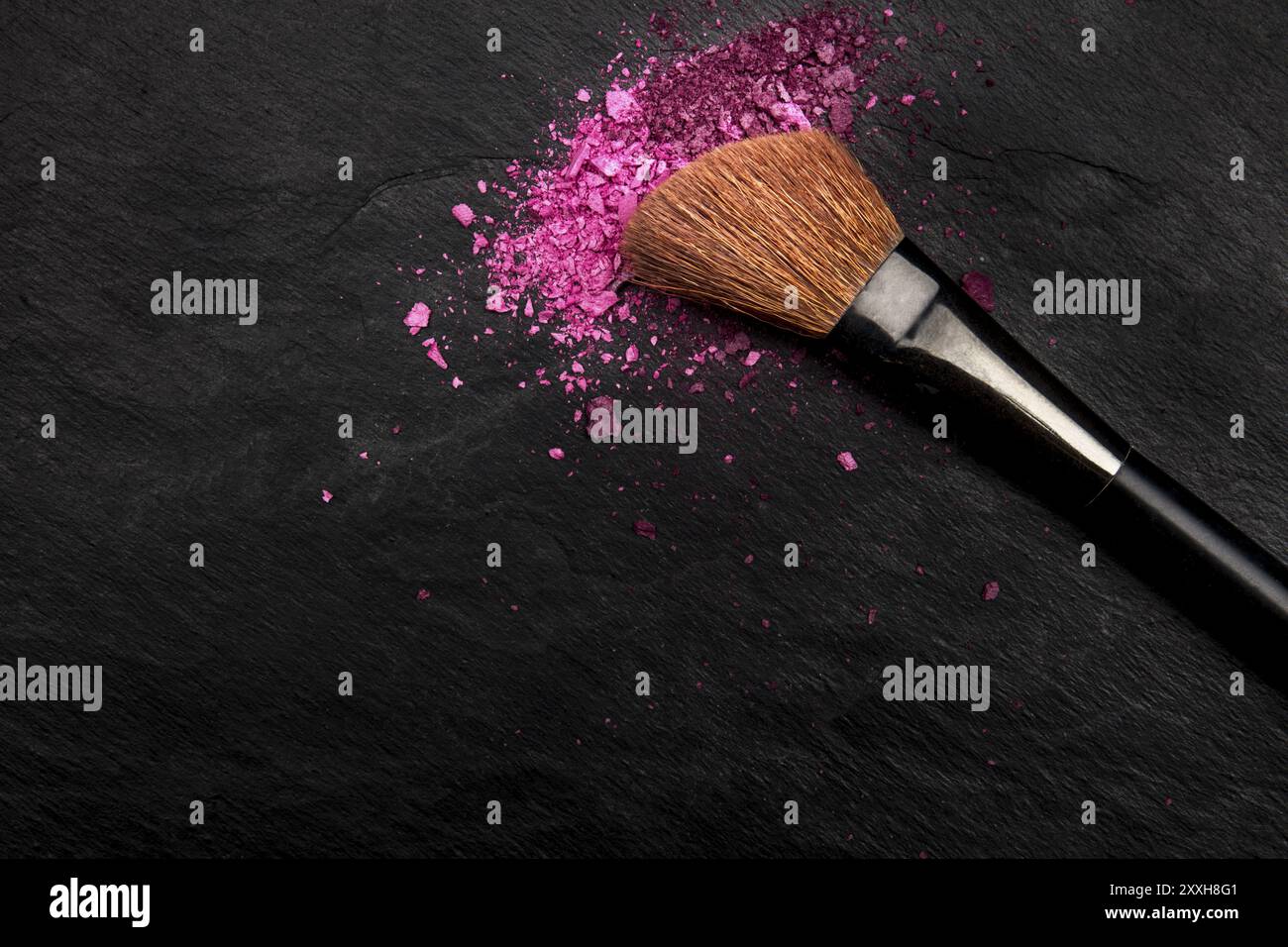 Make-up-Pinsel mit lebendiger, zerdrückter Kosmetik, von oben auf schwarzem Hintergrund mit Platz für Text, eine Schönheitsvorlage für Make-up-Kunst Stockfoto