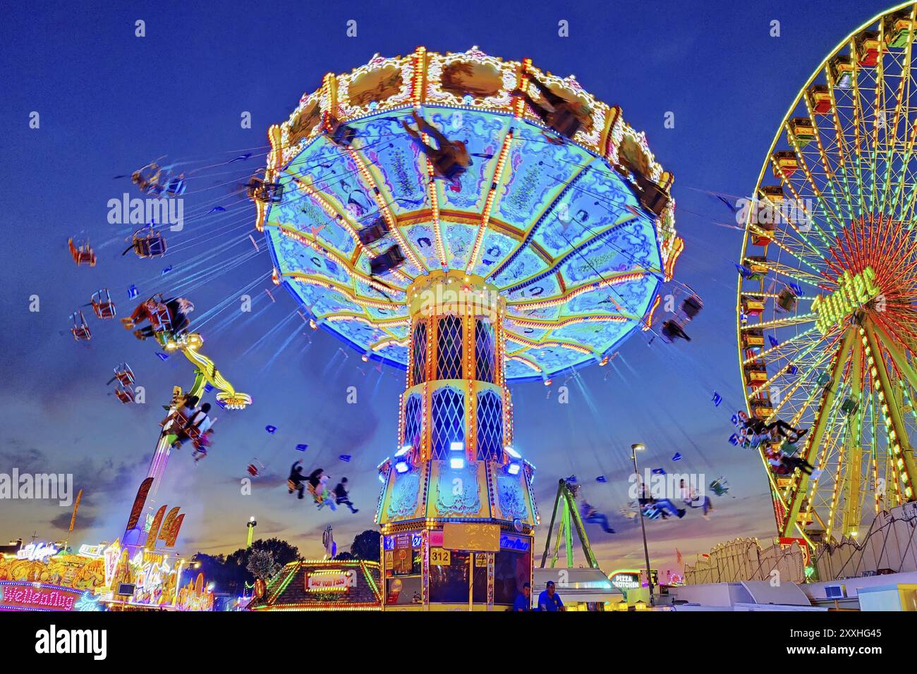 Das bunt beleuchtete Wellenflug Kettenkarussell und das Riesenrad am Abend, Cranger Kirmes, Herne, Ruhrgebiet, Nordrhein-Westfalen, G Stockfoto