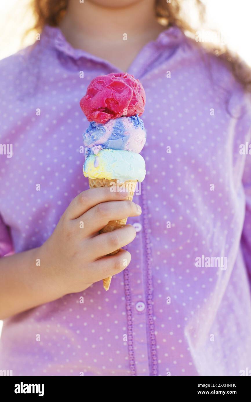 Kleines lächelndes Mädchen, das draußen Eisbecher in den Händen hält Stockfoto