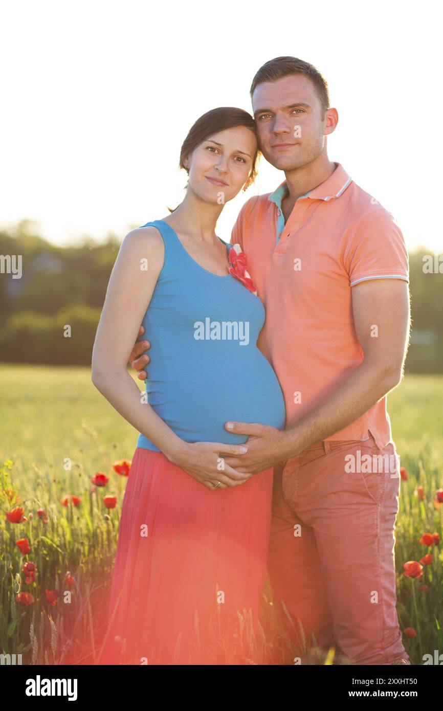 Portrait einer jungen schönen schwangeren Paare im Mohnfeld Stockfoto