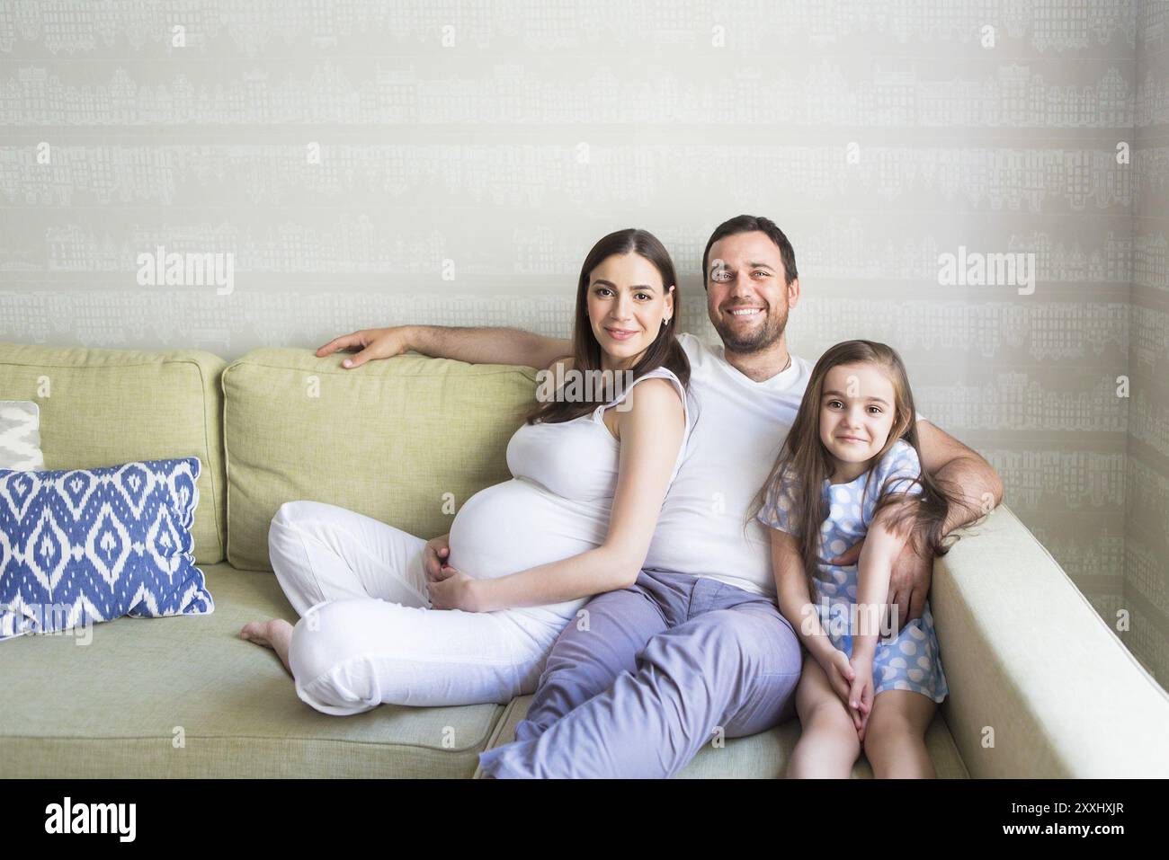 Adorable junge schwangere Familie im Wohnzimmer. Glück und Liebe Konzept Stockfoto