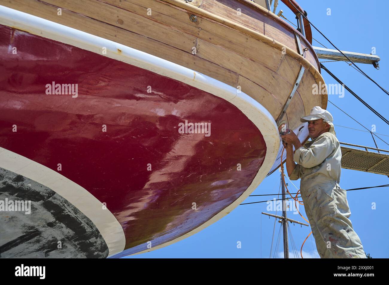 Ein Arbeiter arbeitet am roten Rumpf eines Segelschiffes, Patmos Marine, Bootswerft, Diakofti, Patmos, Dodekanesisch, Griechische Inseln, Griechenland, Europa Stockfoto