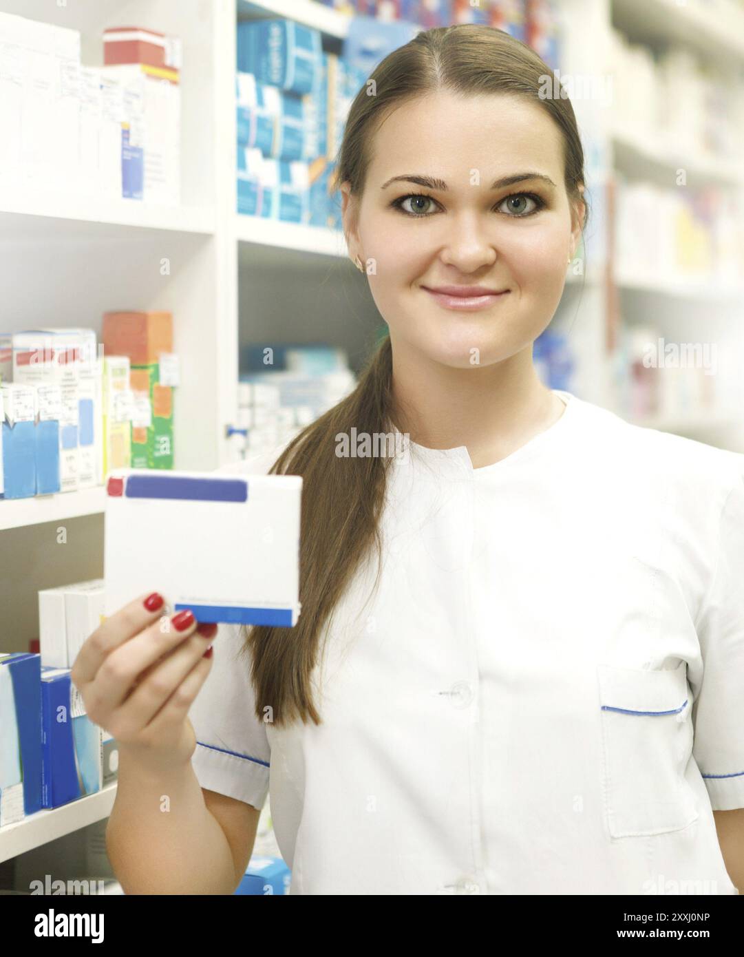 Porträt des jungen Apothekerin zeigt Medizin-Box bei Apotheke Zähler Stockfoto
