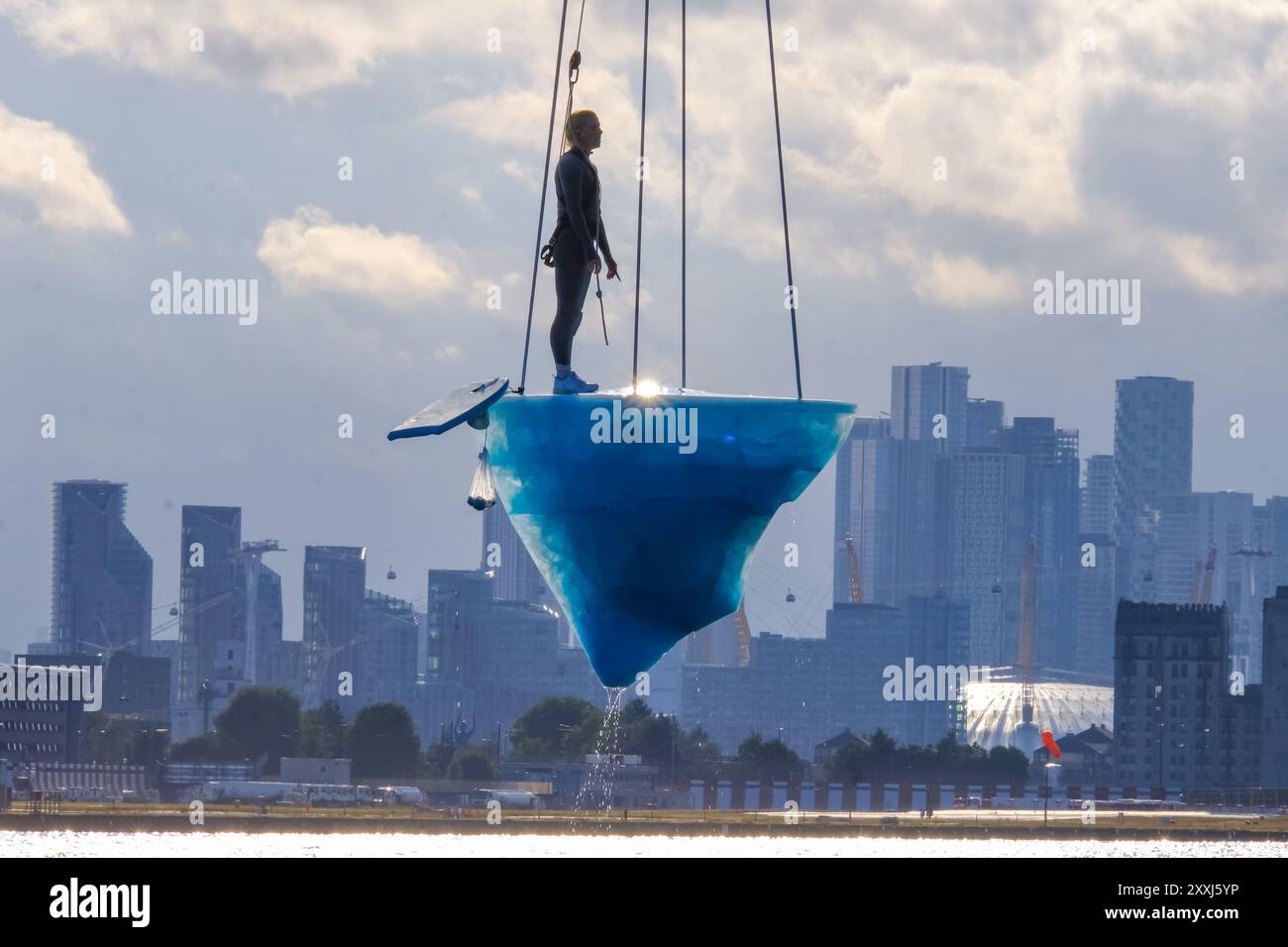 London, UK, 24. August 2024. Bei der europäischen Premiere von 'TAW' beim Greenwich+Docklands International Festival (GDIF) waren drei Luftkünstler auf einem schmelzenden 2,5-Tonnen-Eisblock, der über der Gallions Point Marina über acht Stunden schwang. Die am 25. August erneut wiederholte Performance, die von der University of East London in Newham aus zu sehen ist, wurde von der australischen Theaterkompanie Legs on the Wall nach den Buschbränden von 2019/20 geschaffen und fordert die Menschheit auf, die Klimakrise zu bewältigen. Quelle: Eleventh Photography/Alamy Live News Stockfoto