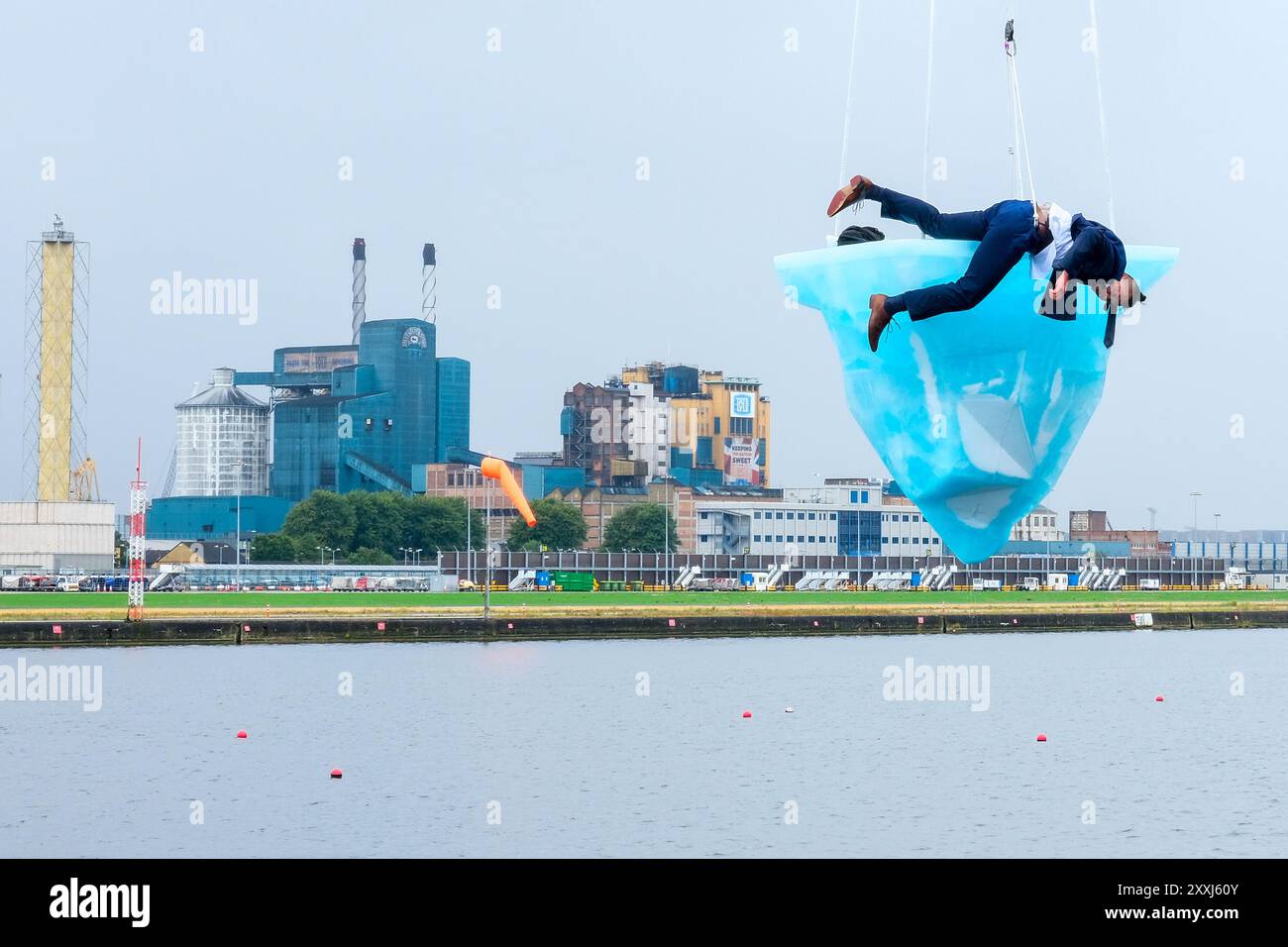 London, UK, 24. August 2024. Bei der europäischen Premiere von 'TAW' beim Greenwich+Docklands International Festival (GDIF) waren drei Luftkünstler auf einem schmelzenden 2,5-Tonnen-Eisblock, der über der Gallions Point Marina über acht Stunden schwang. Die am 25. August erneut wiederholte Performance, die von der University of East London in Newham aus zu sehen ist, wurde von der australischen Theaterkompanie Legs on the Wall nach den Buschbränden von 2019/20 geschaffen und fordert die Menschheit auf, die Klimakrise zu bewältigen. Quelle: Eleventh Photography/Alamy Live News Stockfoto