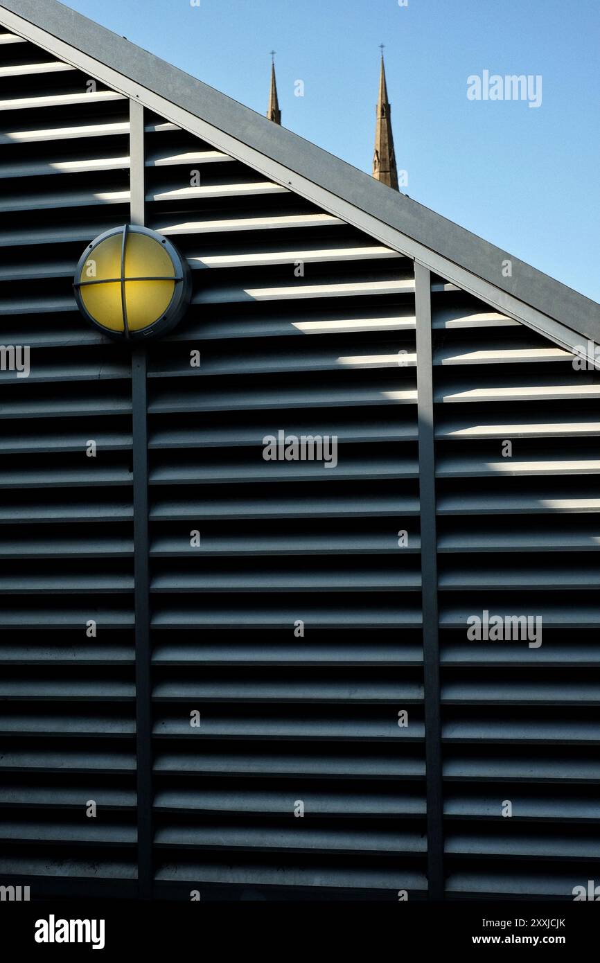 Lüftungsschlitze und Turm im Cook + Phillip Park mit den Spitzen der St. Mays Sandsteintürme, die hinter einem modernen Metallschlitz hervorragen. Sydney, Australien Stockfoto