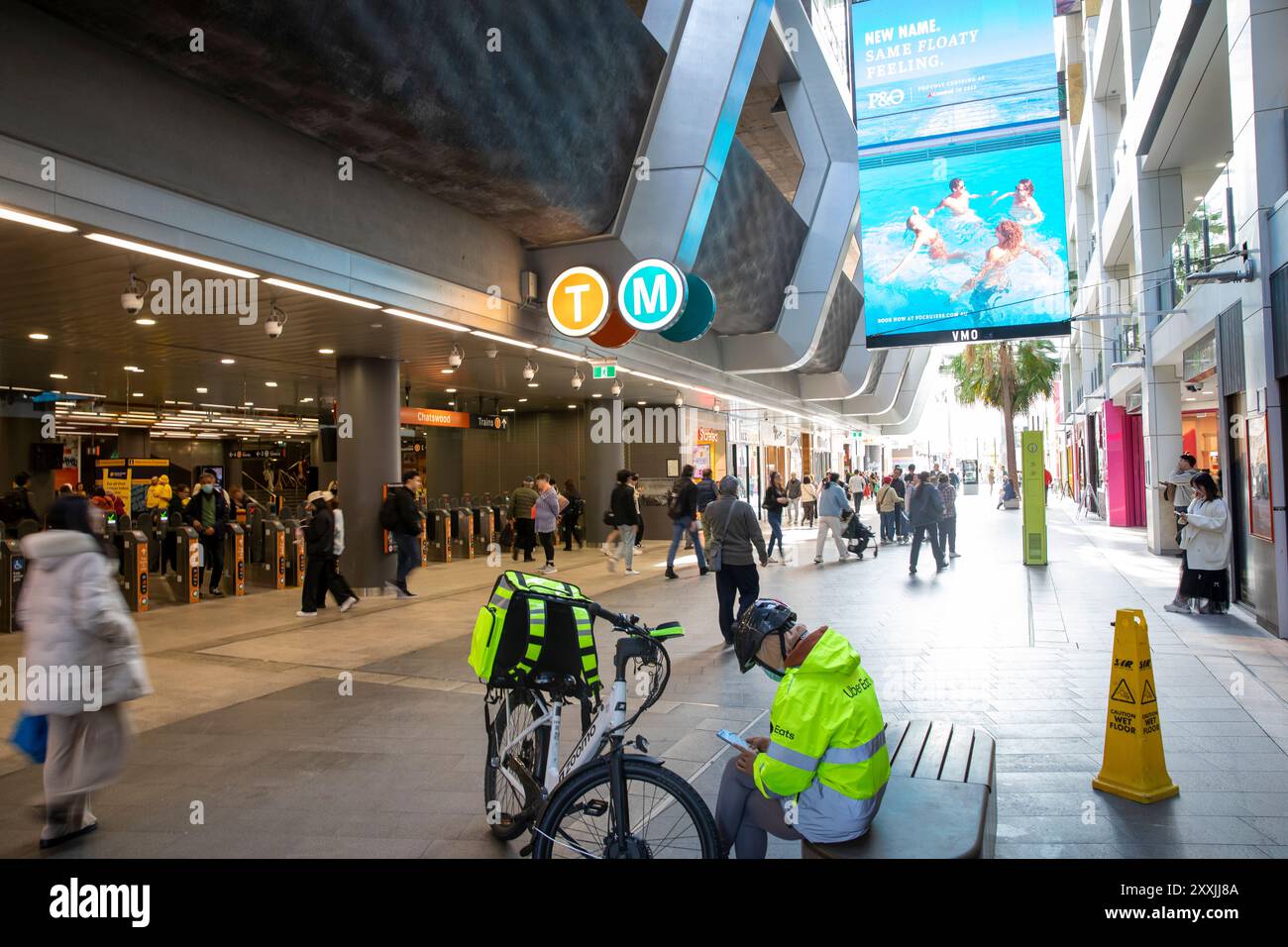 Uber Eats Lieferfahrer machen eine Pause neben Sydney Chatswood Transportstation und Umsteigepunkt, Sydney, NSW, Australien Stockfoto