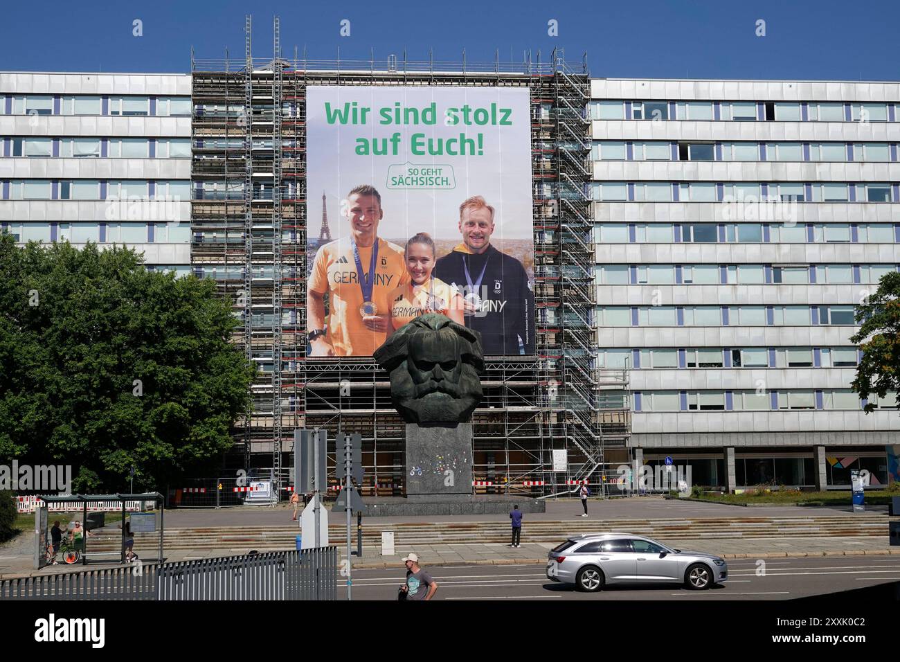 Sächsische Olympiamedaillengewinner Plakat 24.08.2024, Chemnitz, Brückenstraße, Karl-Marx-Denkmal, Chemnitz 23. August 2024 Bronze, Silber, Gold die sportlichen Ausnahmeleistungen der drei sächsischen Olympiagesieger Rebekka Haase, Luca Witzke und Tom Liebscher-Lucz erfahren seit heute 23. August 2024 durch die Kampagne ÂSo geht sächsisch. â eine aufmerksamkeitsstarke und weithin sichtbare Würdigung. Auf einem überdimensionalen großen Fassadenbanner von 18x20 Metern in der Chemnitzer Innenstadt, direkt hinter dem markanten ÂWir, prangt in riesigen Lettern EuchÂ sind stolz auf ÂNischlÂ. Darunter Stockfoto