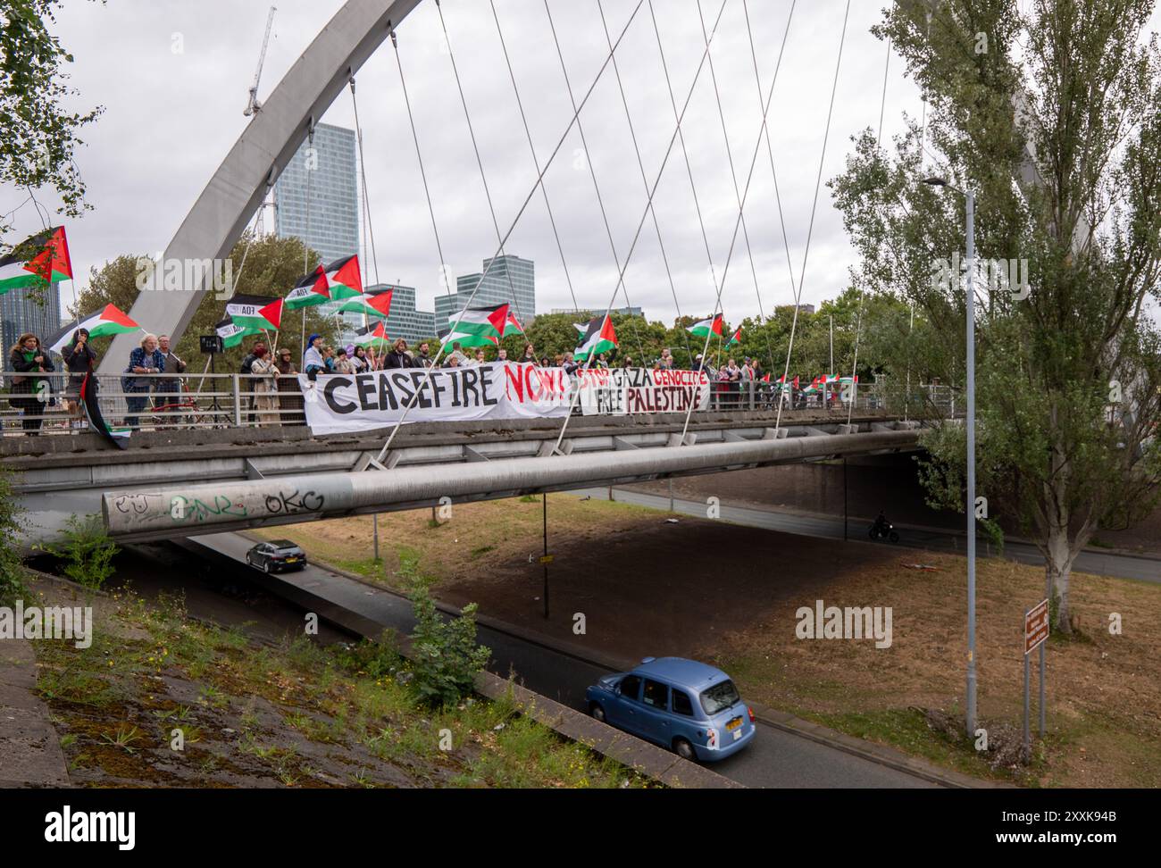 Manchester, Großbritannien. August 2024. Palästinensische Demonstranten besetzen die Straßenbrücke über die befahrene Princess Road (A5103), eine Hauptstraße, die nach Manchester führt. Um 12.00 Uhr wurden auf beiden Seiten der Brücke, die für den Hulme-Bogen berühmt ist, Banner ausgeklappt, was dazu führte, dass die Polizei eine der Fahrbahnen der Duellstraße blockierte und sich Verkehr aufbaute. Die Straße wird aufgrund des Feiertags-Wochenendes und des Manchester Pride 2024 Festivals im Stadtzentrum besonders stark frequentiert sein. Quelle: GaryRobertsphotography/Alamy Live News Stockfoto