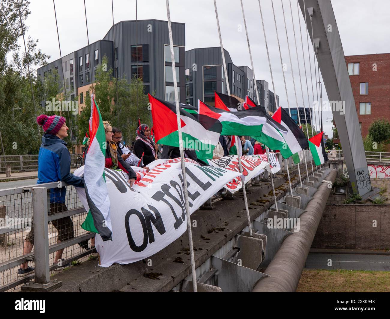 Manchester, Großbritannien. August 2024. Palästinensische Demonstranten besetzen die Straßenbrücke über die befahrene Princess Road (A5103), eine Hauptstraße, die nach Manchester führt. Um 12.00 Uhr wurden auf beiden Seiten der Brücke, die für den Hulme-Bogen berühmt ist, Banner ausgeklappt, was dazu führte, dass die Polizei eine der Fahrbahnen der Duellstraße blockierte und sich Verkehr aufbaute. Die Straße wird aufgrund des Feiertags-Wochenendes und des Manchester Pride 2024 Festivals im Stadtzentrum besonders stark frequentiert sein. Quelle: GaryRobertsphotography/Alamy Live News Stockfoto