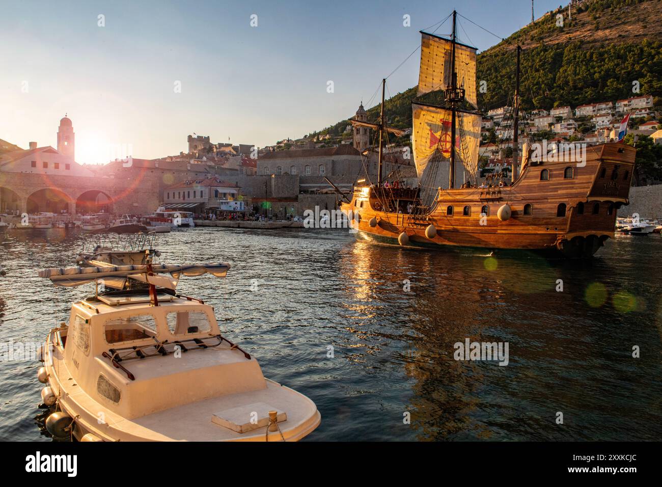 Eine Schaluppe und kleine Boote in der Abenddämmerung im Hafen von Dubrovnik, Kroatien Stockfoto