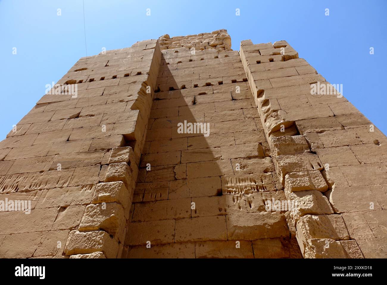 Besucher beobachten die riesigen, verwitterten Pylonen des Tempelkomplexes Karnak in Ägypten, die alte Architektur vor einem leuchtend blauen Himmel zeigen. Stockfoto