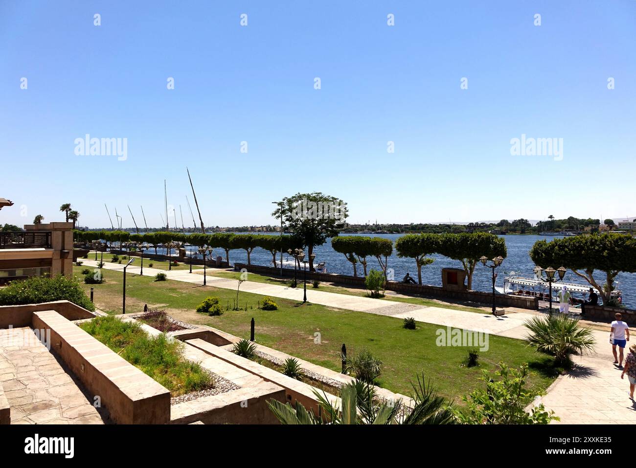 Besucher schlendern entlang der malerischen Promenade am Nil in Luxor und genießen die atemberaubende Aussicht und lebhafte Atmosphäre dieses historischen Ortes Stockfoto