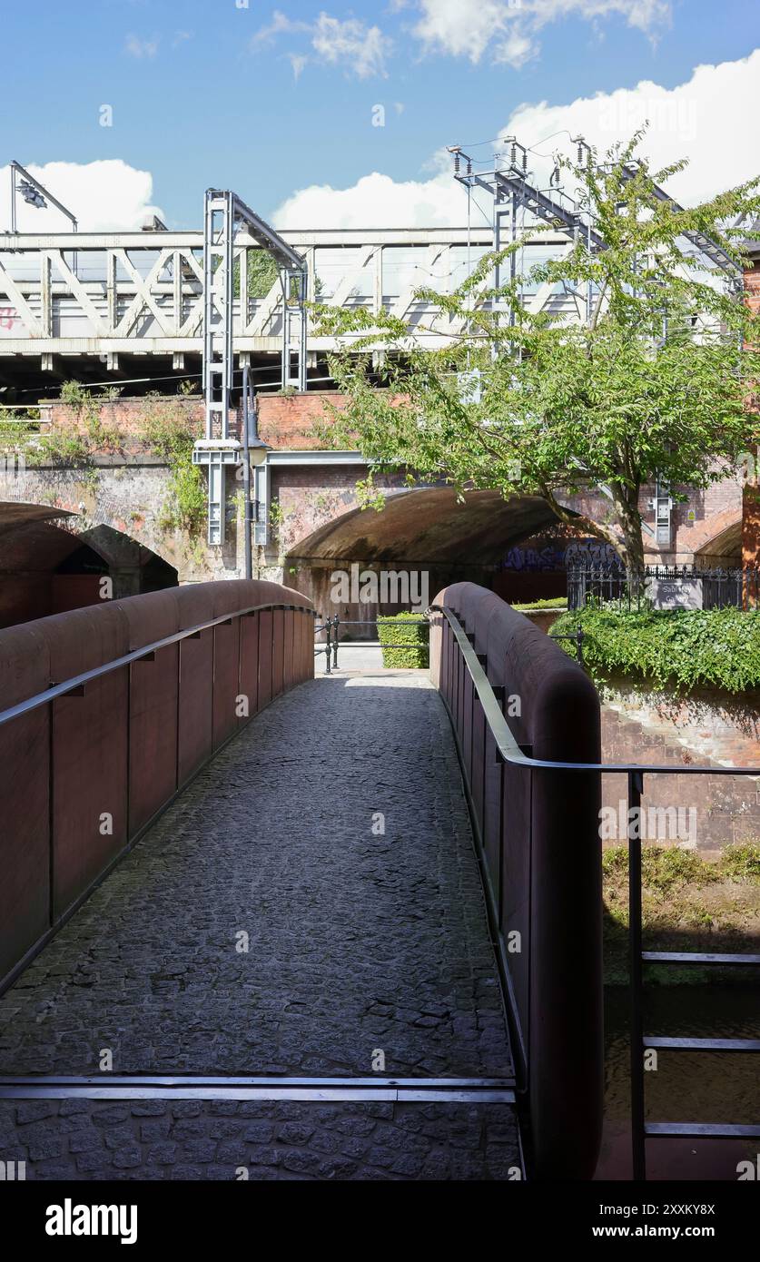 Manchester, Greater Manchester, Großbritannien. 24. August 2024: Fußgängerbrücke über einen Kanal mit überkopfem Eisenbahngelände. Stockfoto