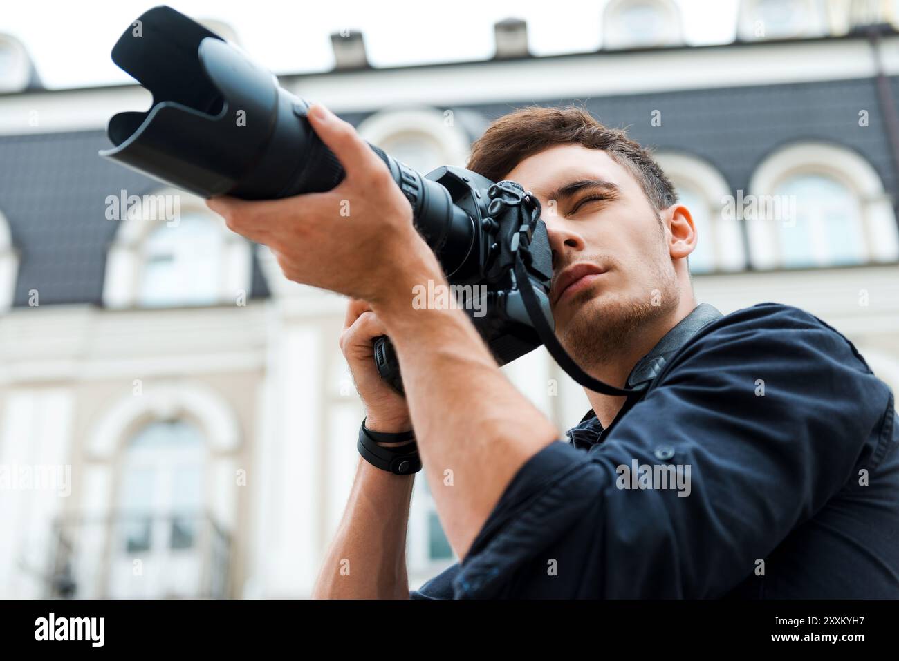 Machen Sie eine perfekte Aufnahme. Niedriger Blickwinkel eines jungen Mannes, der etwas fotografiert, während er draußen steht Stockfoto