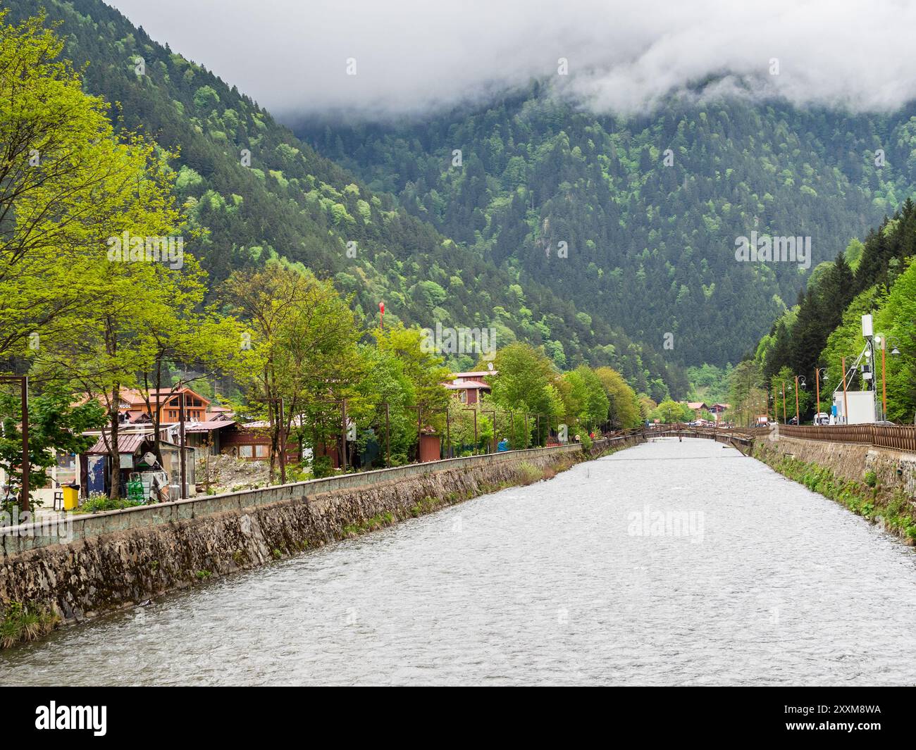 Wasserkanal im Dorf Uzungol in grün bewachsenen Bergen im Bezirk Caykara der Provinz Trabzon, Türkei an bewölktem Sommertag Stockfoto